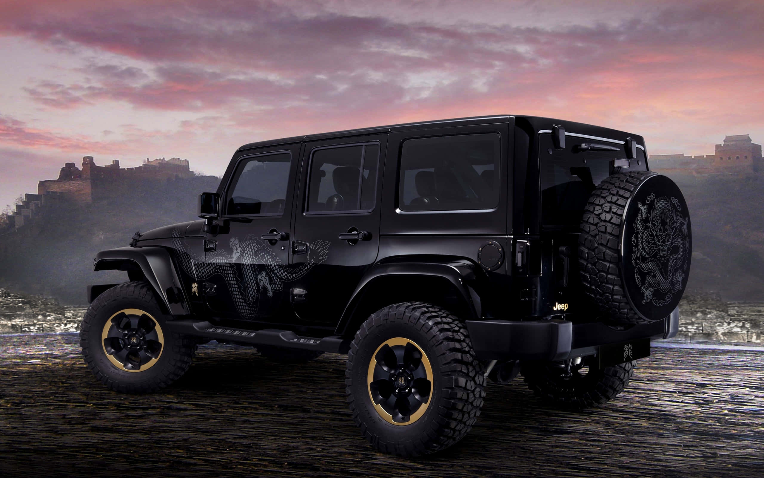 黑色吉普車 桌布 壁紙 — 一輛黑色Jeep Wrangler配金色輪圈和龍形貼紙，停在岩石小徑上，背景是粉紫色夕陽天空和古老城堡廢墟。
