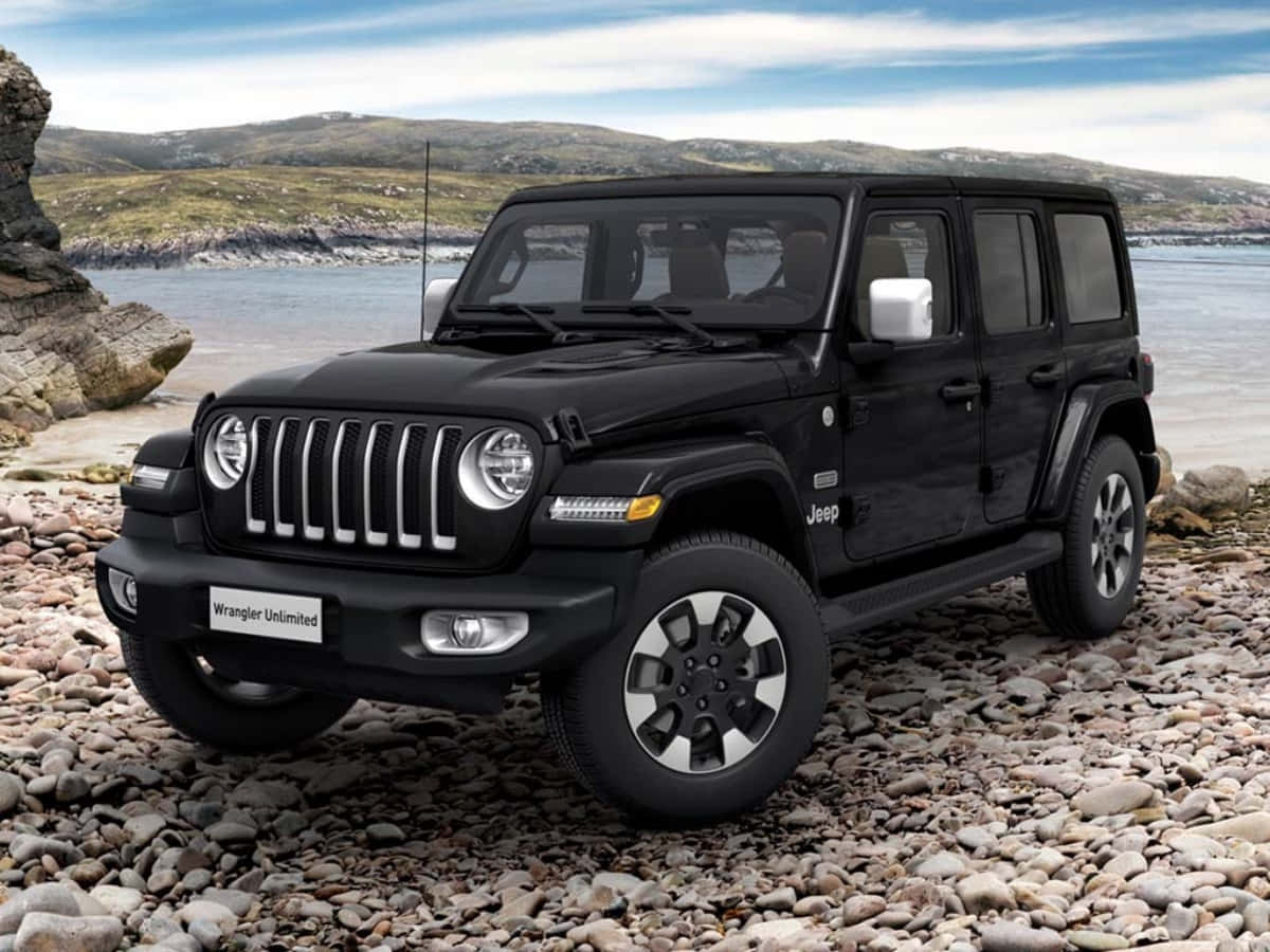黑色吉普車 桌布 壁紙 — 一輛黑色Jeep Wrangler Unlimited大膽地矗立在岩石海岸線上，平靜的水面和起伏的丘陵在部分多雲的天空下。