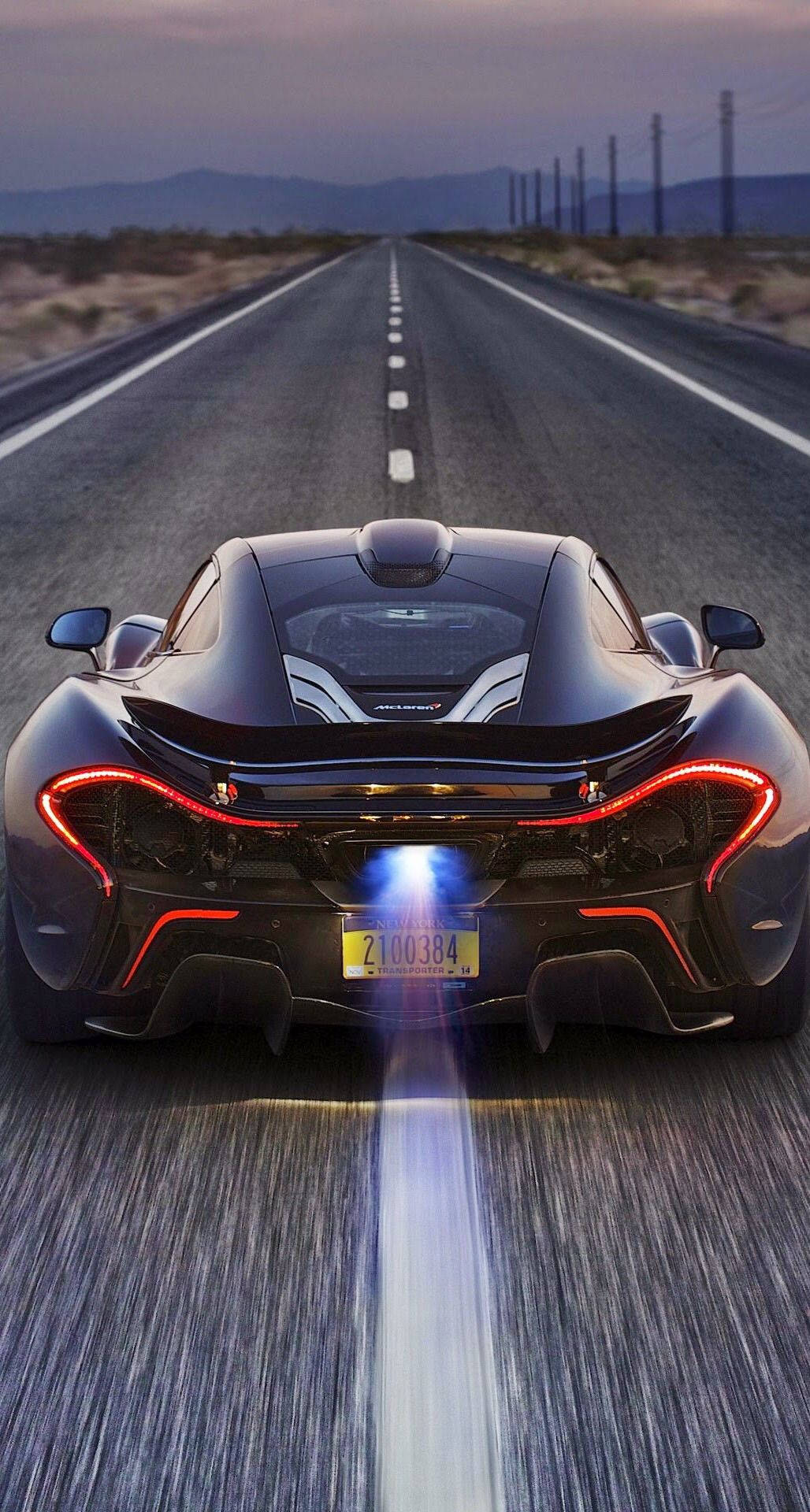 cars 桌布 壁紙 — 一輛黑色McLaren P1在黃昏時分於沙漠公路上疾馳，帶有發光的紅色尾燈和藍色排氣火焰。