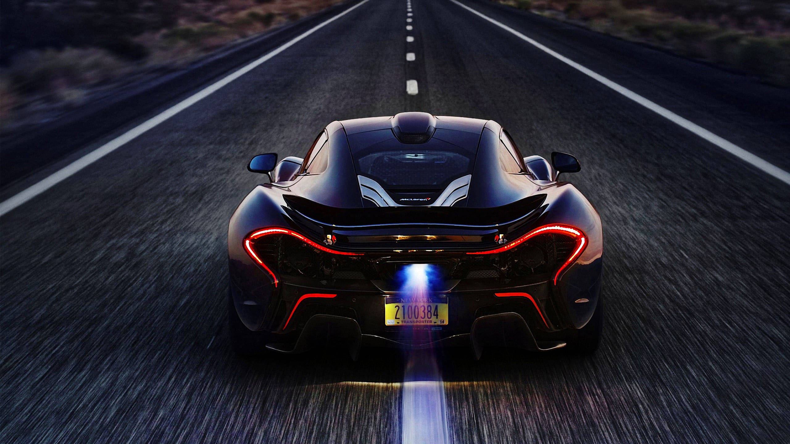Road 桌布 壁紙 — 一輛黑色McLaren P1在黃昏時分於沙漠公路上疾馳，帶有發光的紅色尾燈和藍色排氣火焰。