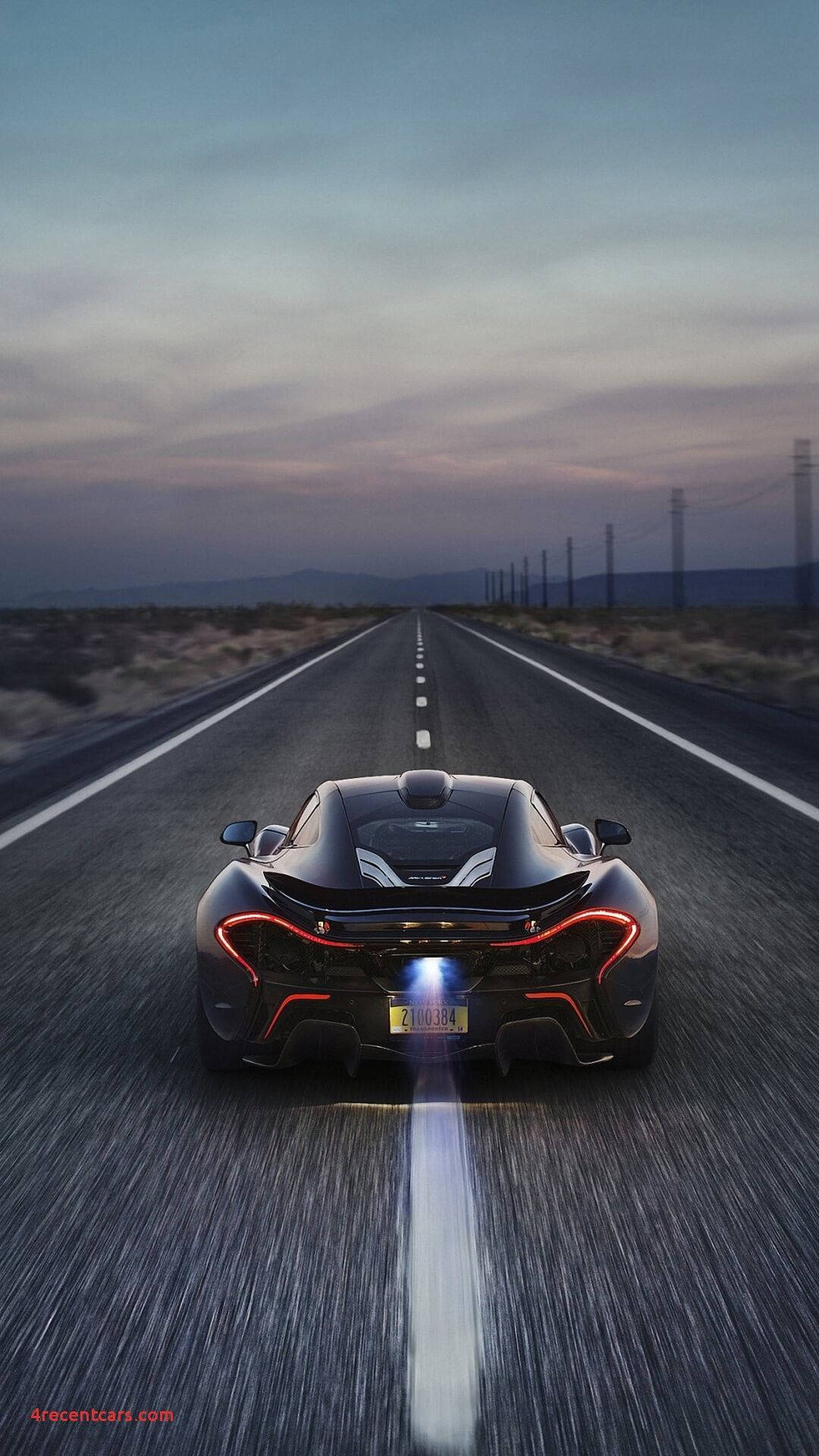 Cell 桌布 壁紙 — 一輛黑色McLaren跑車在黃昏時分沿沙漠高速公路奔馳，帶有紅色尾燈和動態模糊效果。
