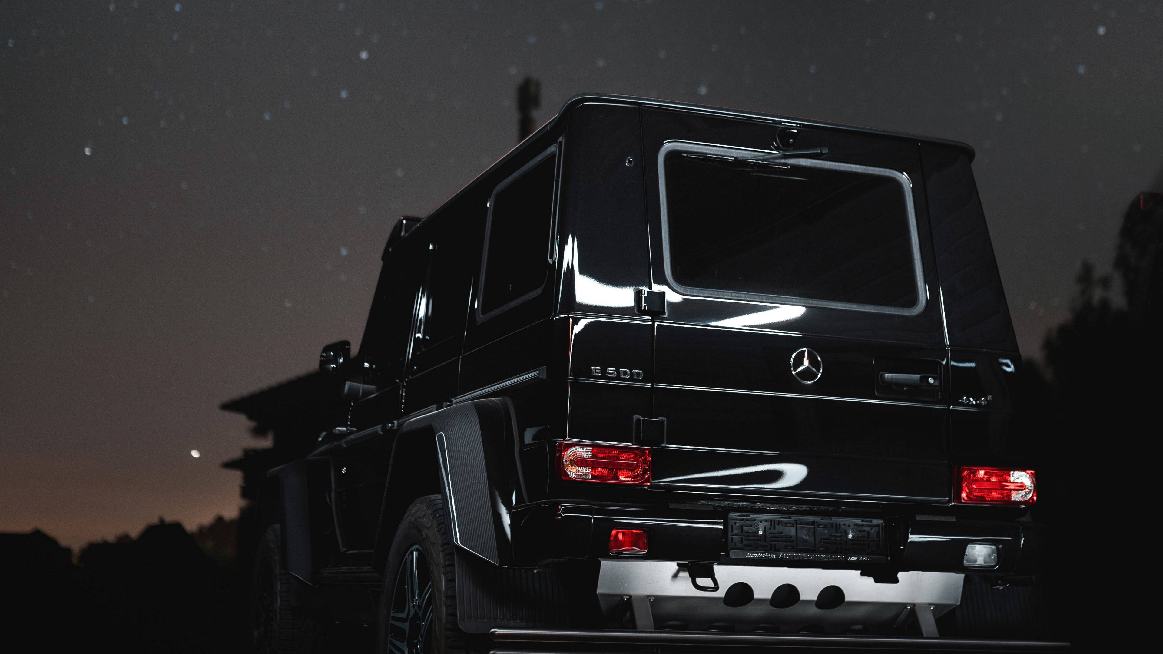 4K 奔馳壁紙 桌布 壁紙 — 一輛黑色Mercedes G-Class SUV停在星空下，紅色尾燈閃爍，遠處有月亮。