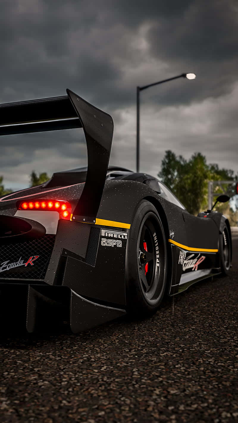 電玩遊戲 桌布 壁紙 — 一輛黑色Zonda R跑車，紅色尾燈發光，停在暴風雨天空下的瀝青路面上。