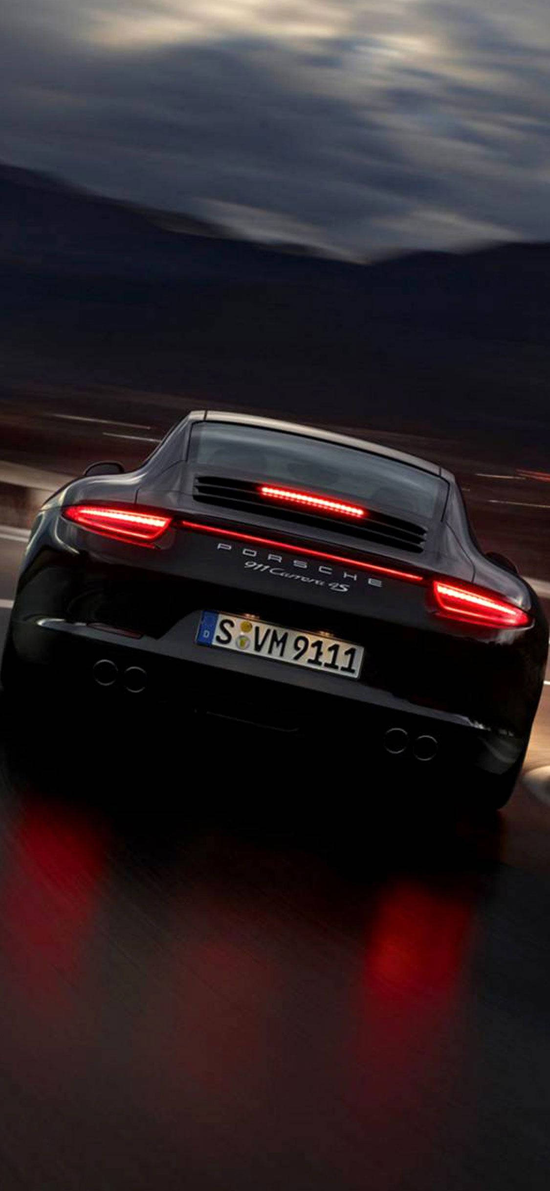 Porsche 911 桌布 壁紙 — 一輛黑色保時捷911 GT3 RS在黃昏時加速駛離，紅色尾燈在潮濕路面上反射。