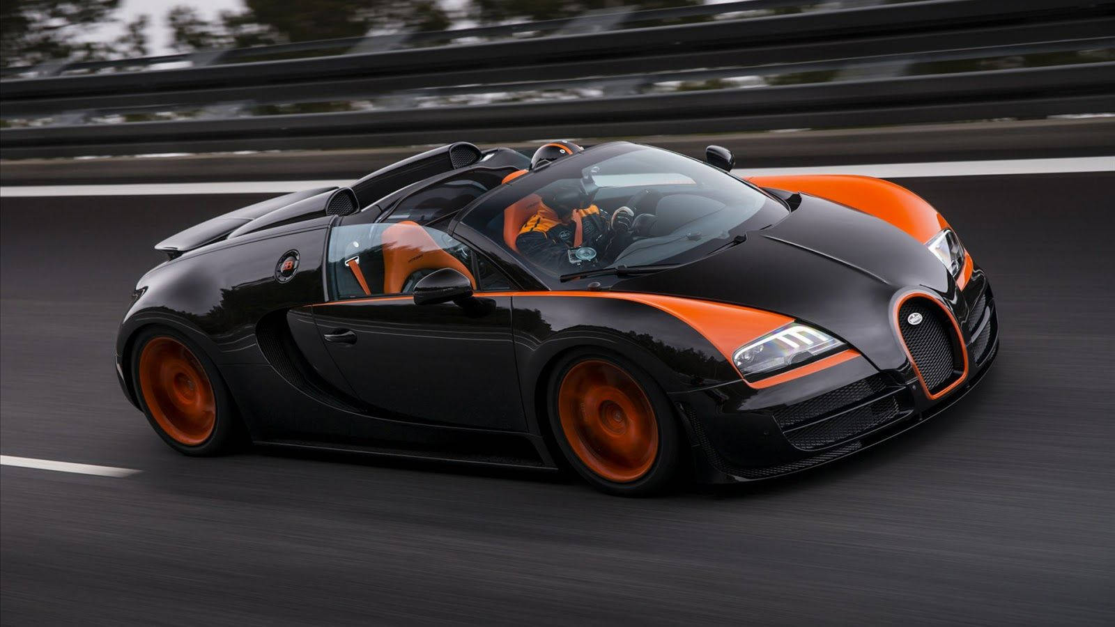 布加迪 桌布 壁紙 — 一輛黑色和橙色的Bugatti Veyron Super Sport在賽道上高速行駛，動態模糊效果突顯其極高速度。
