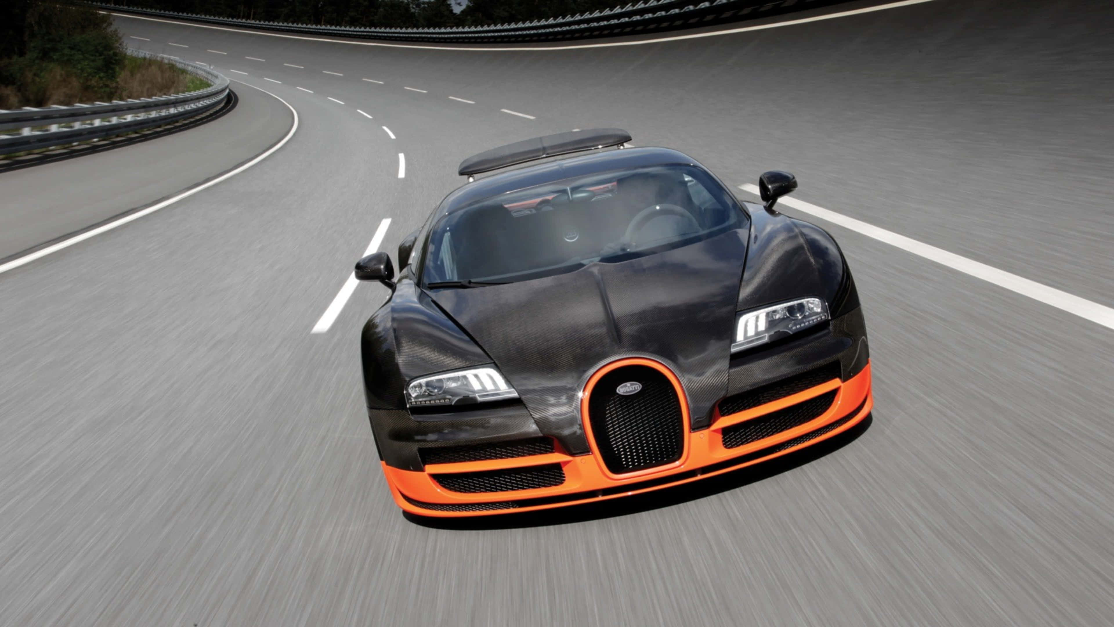 bugatti iPhone 桌布 壁紙 — 一輛黑色和橙色的布加迪威龍在彎曲的山路上疾馳，瀝青運動模糊。