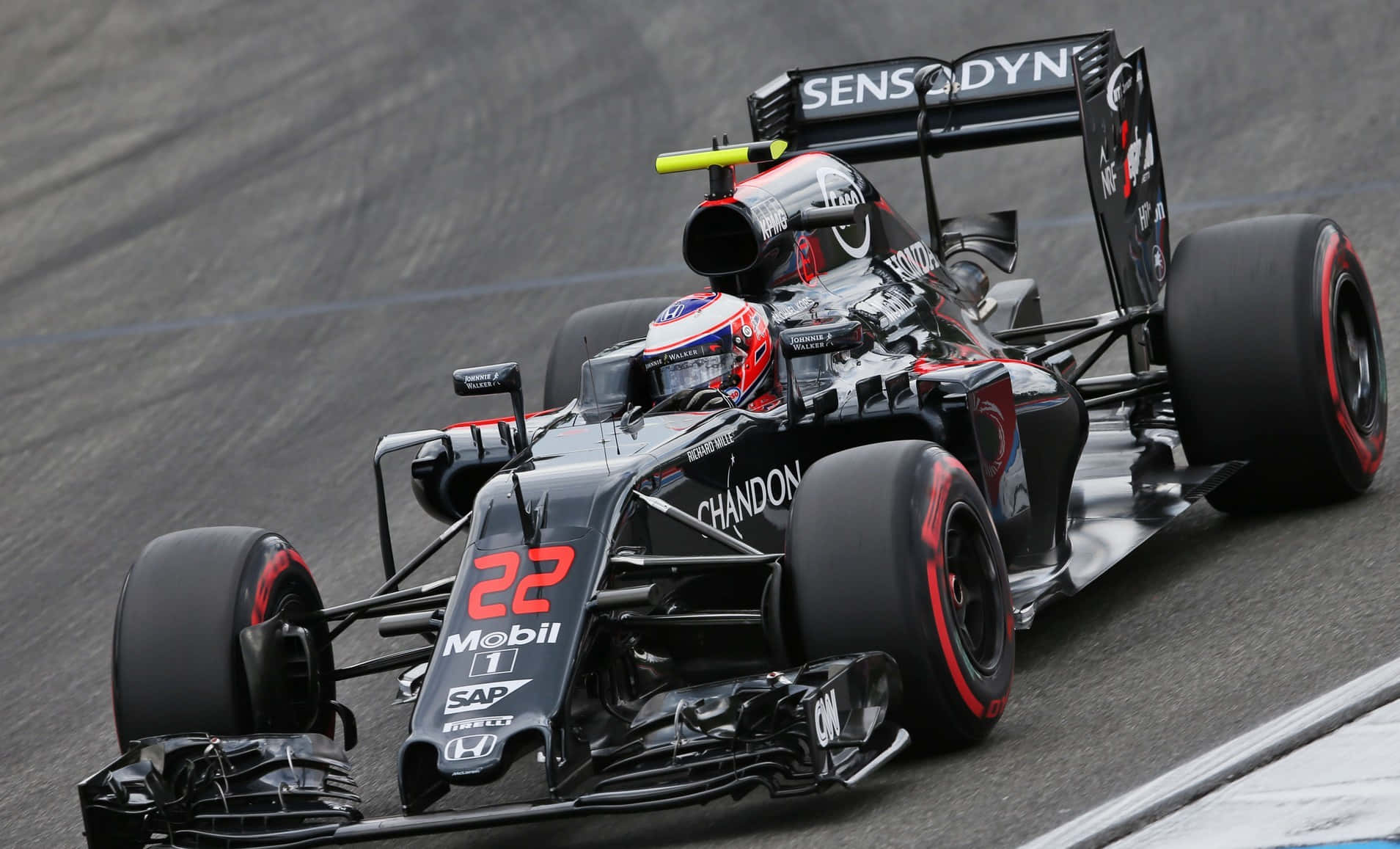 HD F1 2016 桌布 壁紙 — 一輛黑色和紅色、編號22的一級方程式賽車在多雲的天空下於潮濕的賽道上疾馳。