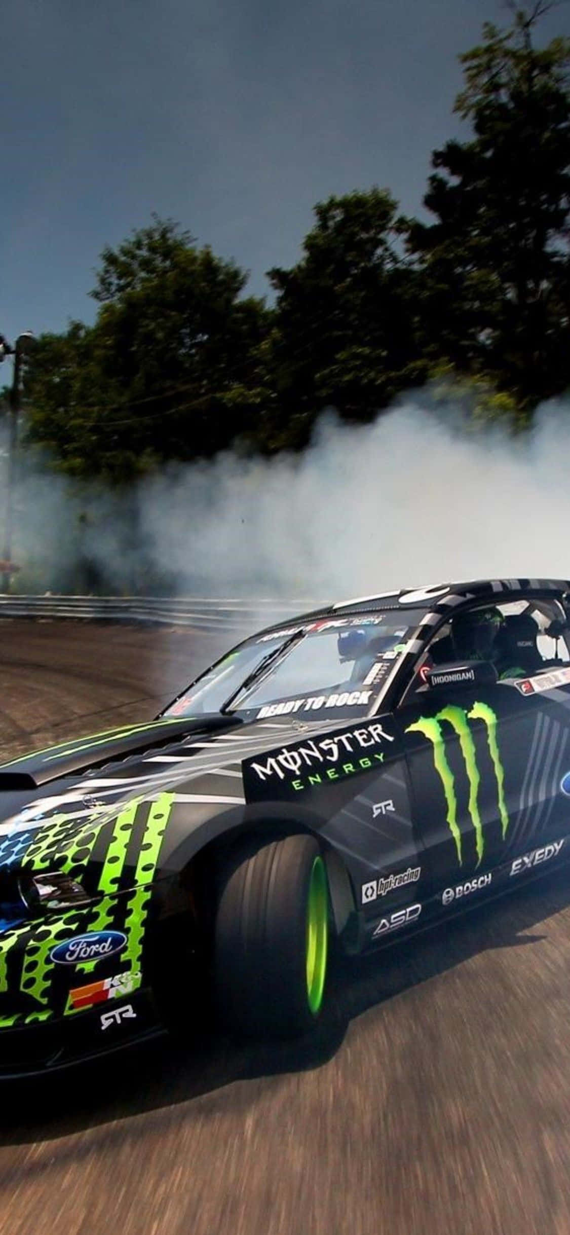 福特 桌布 壁紙 — 一輛黑色和綠色的Monster Energy Ford漂移車在多雲的天空下的賽道上揚起煙霧。