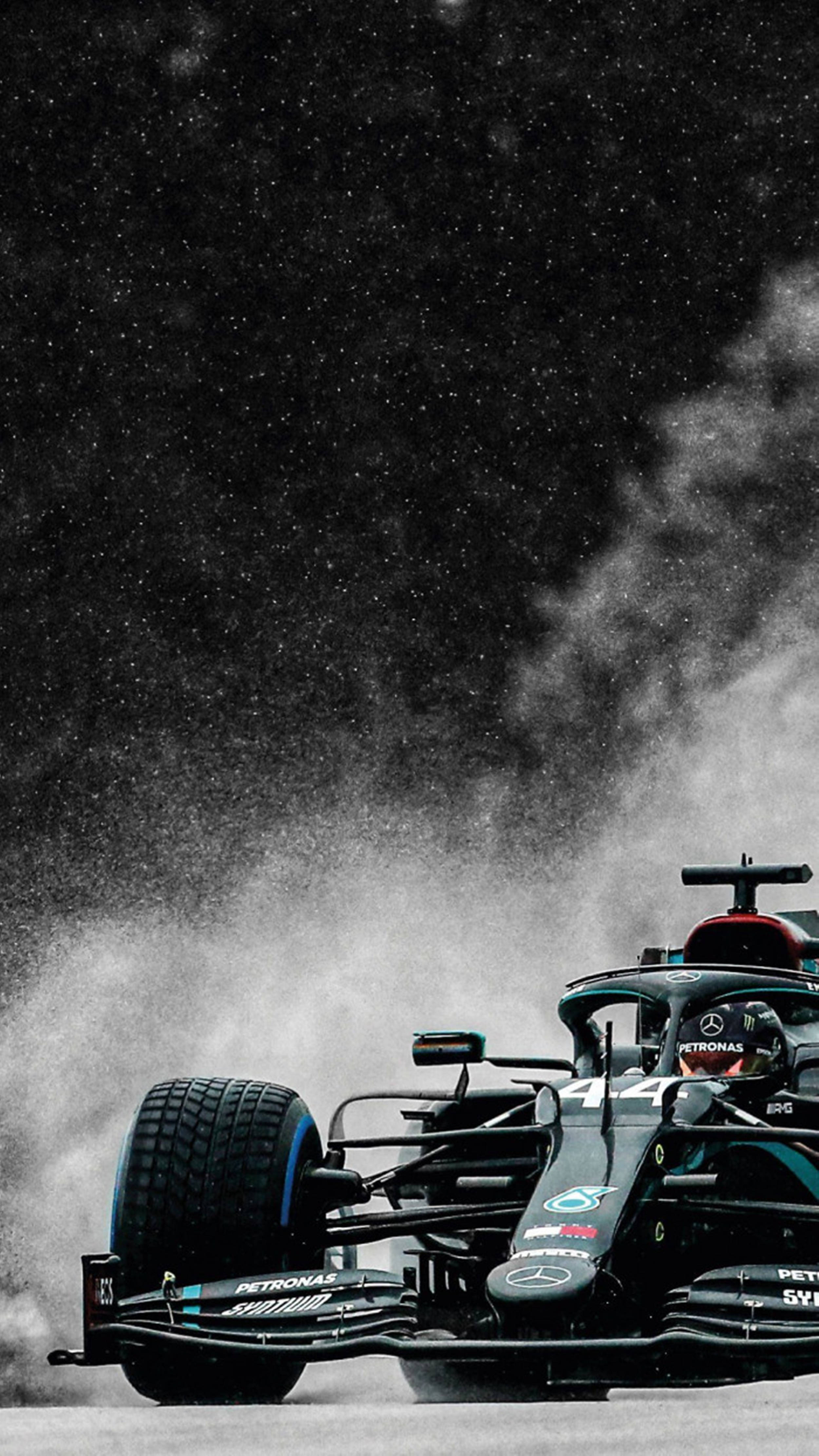 F1 桌布 壁紙 — 一輛黑色和藍綠色的F1賽車在繁星點點的夜空下揚起塵土，煙霧在車尾盤旋。
