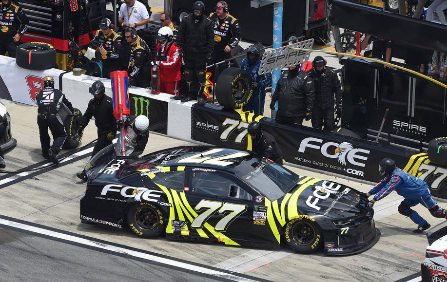人物 桌布 壁紙 — 一輛黑色和螢光黃色的NASCAR賽車77號正在比賽期間由車隊成員在維修站進行維修。