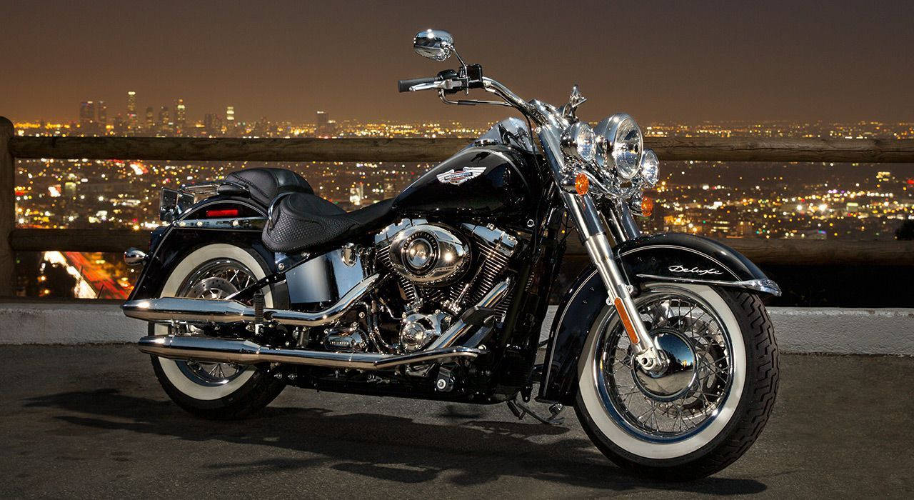 Harley 桌布 壁紙 — 一輛黑色哈雷戴維森摩托車在夜燈下閃閃發光，背後是廣闊的城市景觀閃爍。