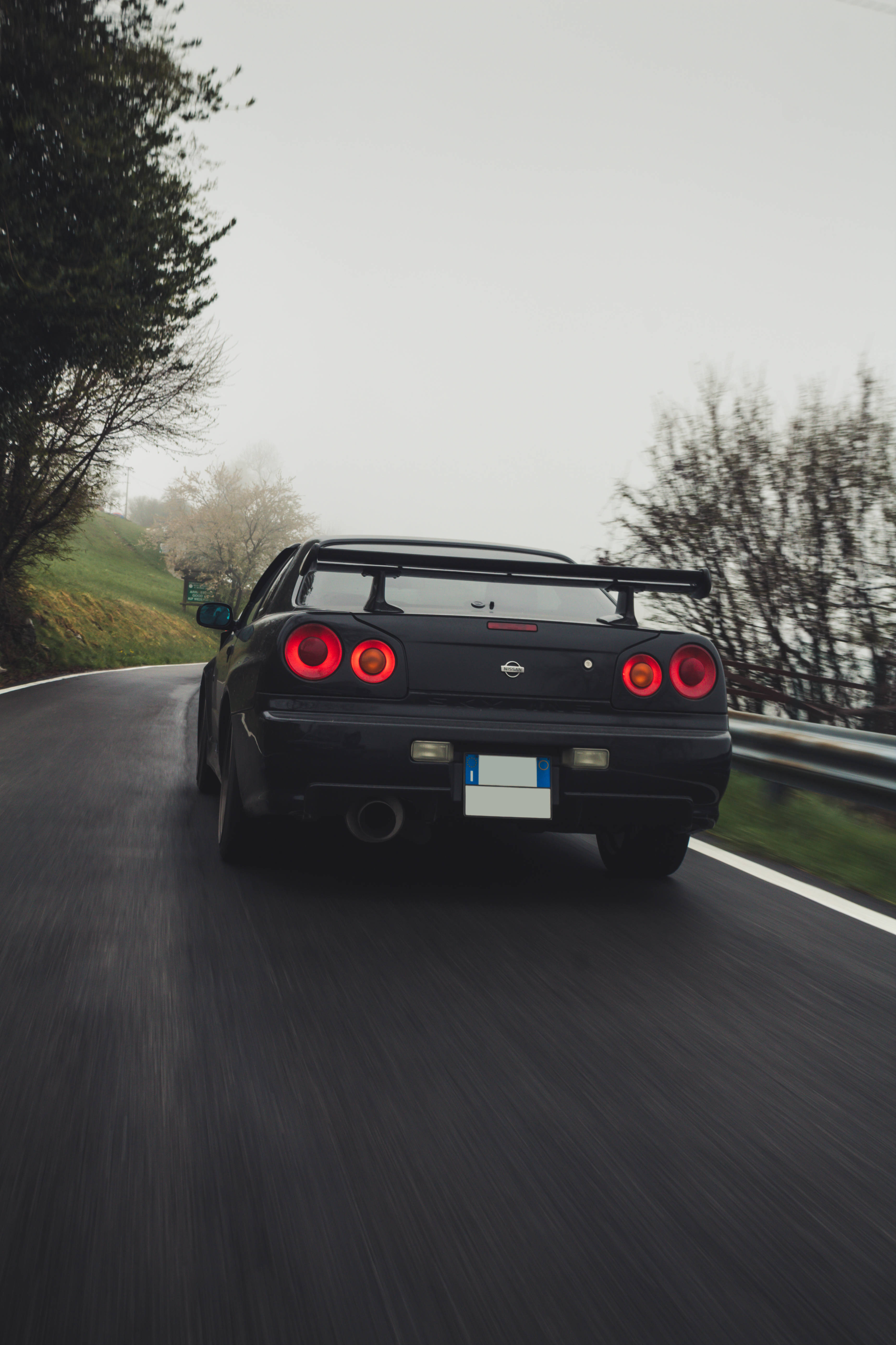 Nissan 桌布 壁紙 — 一輛黑色日產R34 GT-R在霧氣瀰漫的山路上疾馳，紅色尾燈閃爍，動作模糊。
