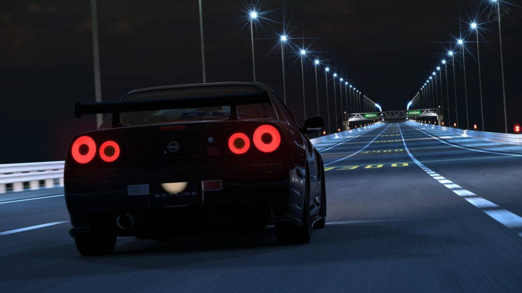 Need For Speed 桌布 壁紙 — 一輛黑色日產Skyline R34在夜間沿著明亮的高速公路飛馳，帶有發光的紅色圓形尾燈。