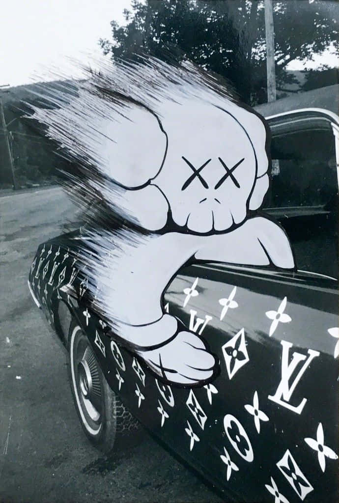 Cool Kaws 桌布 壁紙 — 一輛黑色汽車，車身覆蓋白色路易威登字母圖案塗鴉，側面繪有一個大型卡通骷髏角色。