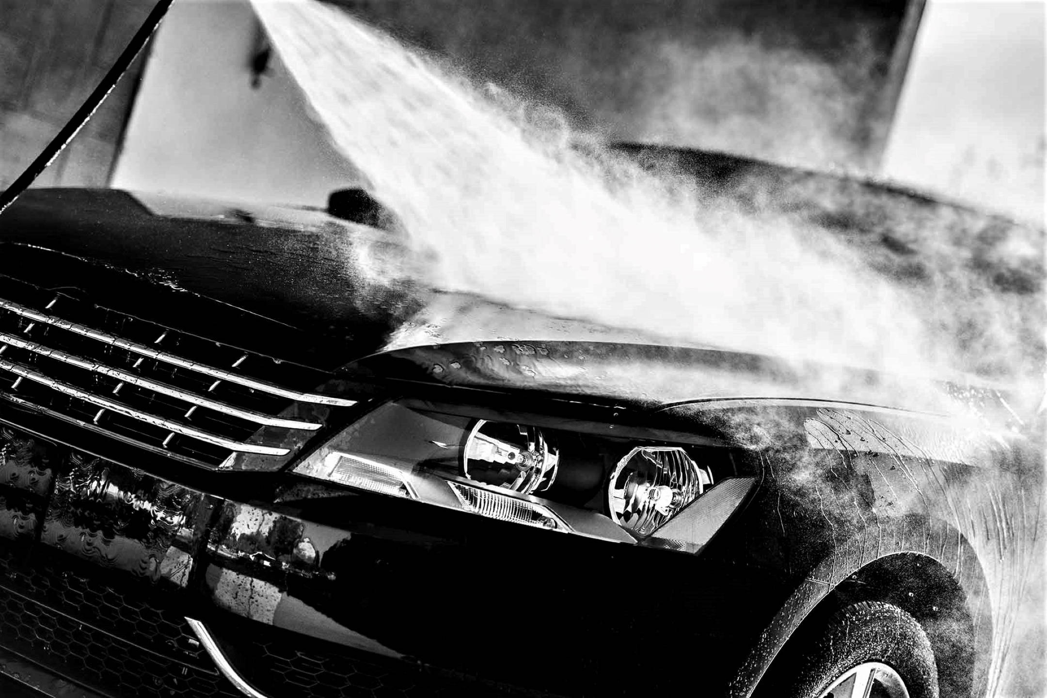 Wash 桌布 壁紙 — 一輛黑色汽車正被強力水柱高壓清洗，在引擎蓋和格柵上形成霧狀噴霧。