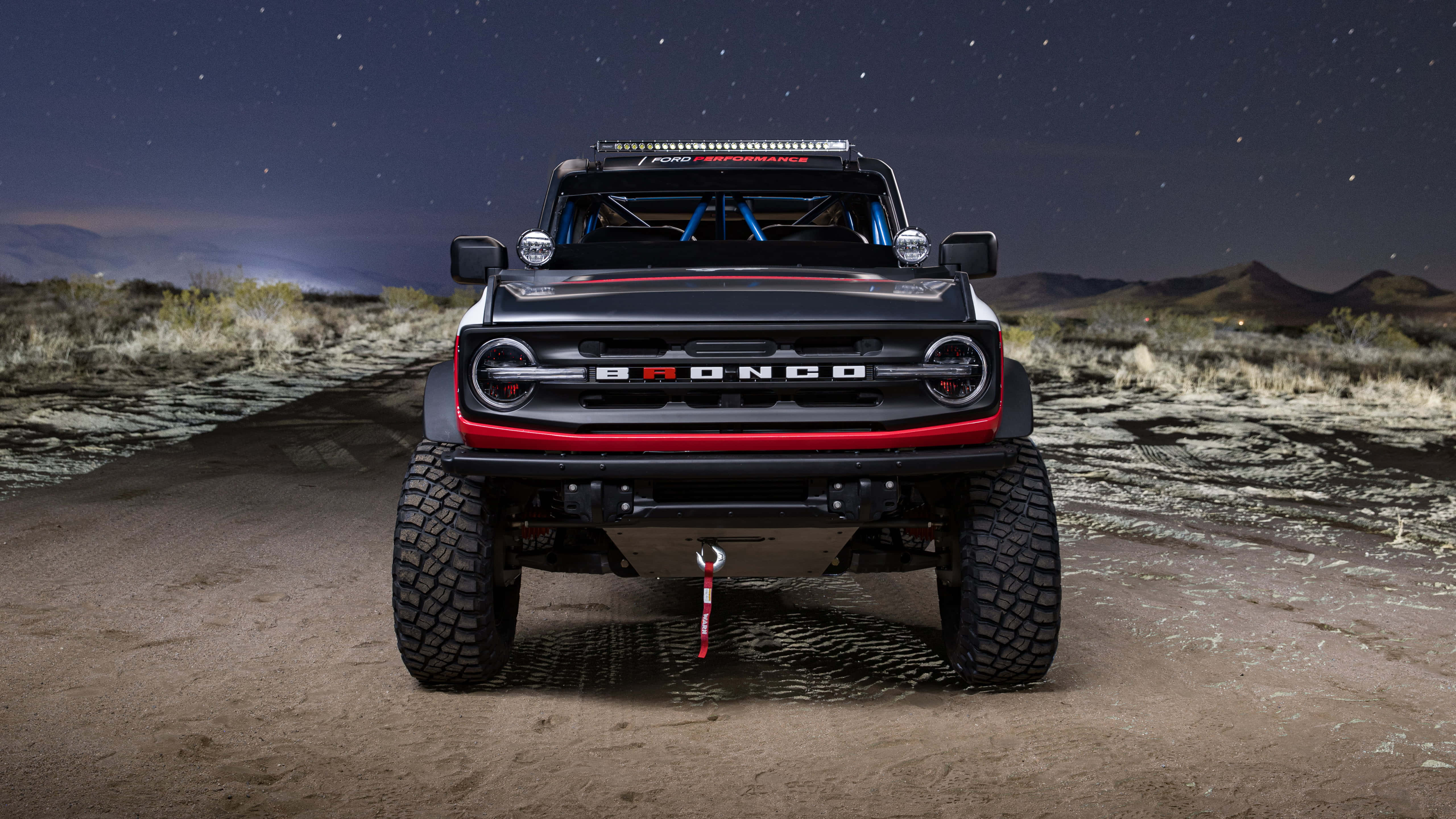 Ford Bronco 桌布 壁紙 — 一輛黑色福特Bronco帶有紅色點綴，正面朝向星空下的沙漠小徑。