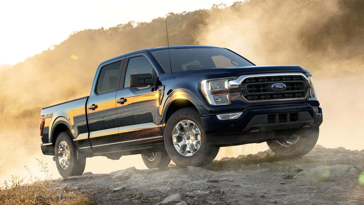 Ford F 150 桌布 壁紙 — 一輛黑色福特F-150皮卡車在日落時分駛過岩石地形，揚起灰塵。