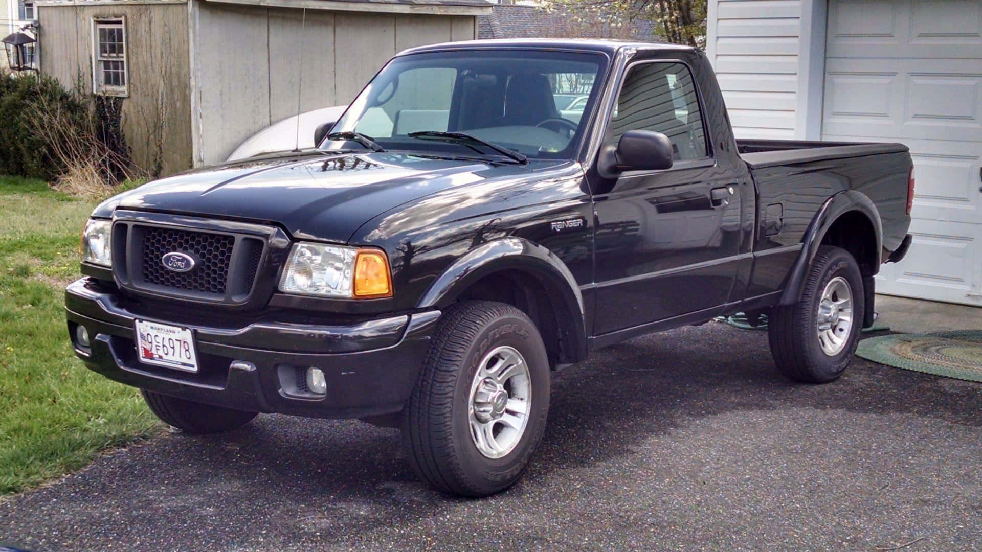 Ford Ranger 桌布 壁紙 — 一輛黑色福特Ranger pickup貨車停放在碎石車道上，旁邊是白色車庫，背景有綠色草地和木棚。