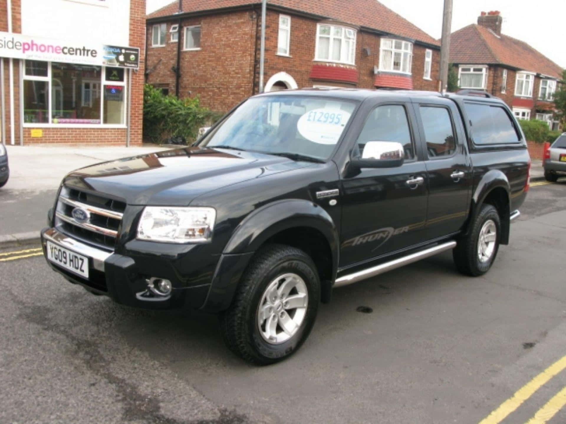 Ford Ranger 桌布 壁紙 — 一輛黑色福特Ranger皮卡車停在一條街上，背景有磚房和電話中心。