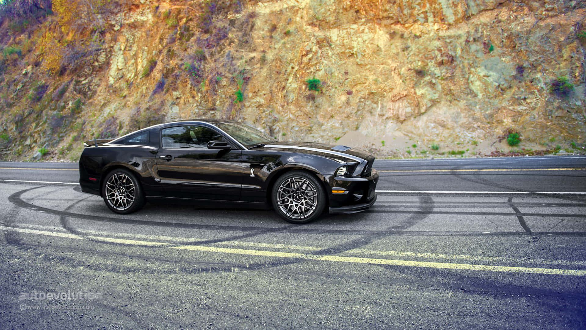福特 桌布 壁紙 — 一輛黑色福特野馬Shelby GT500在蜿蜒的山路上進行燒胎表演，背景是崎嶇的懸崖峭壁。