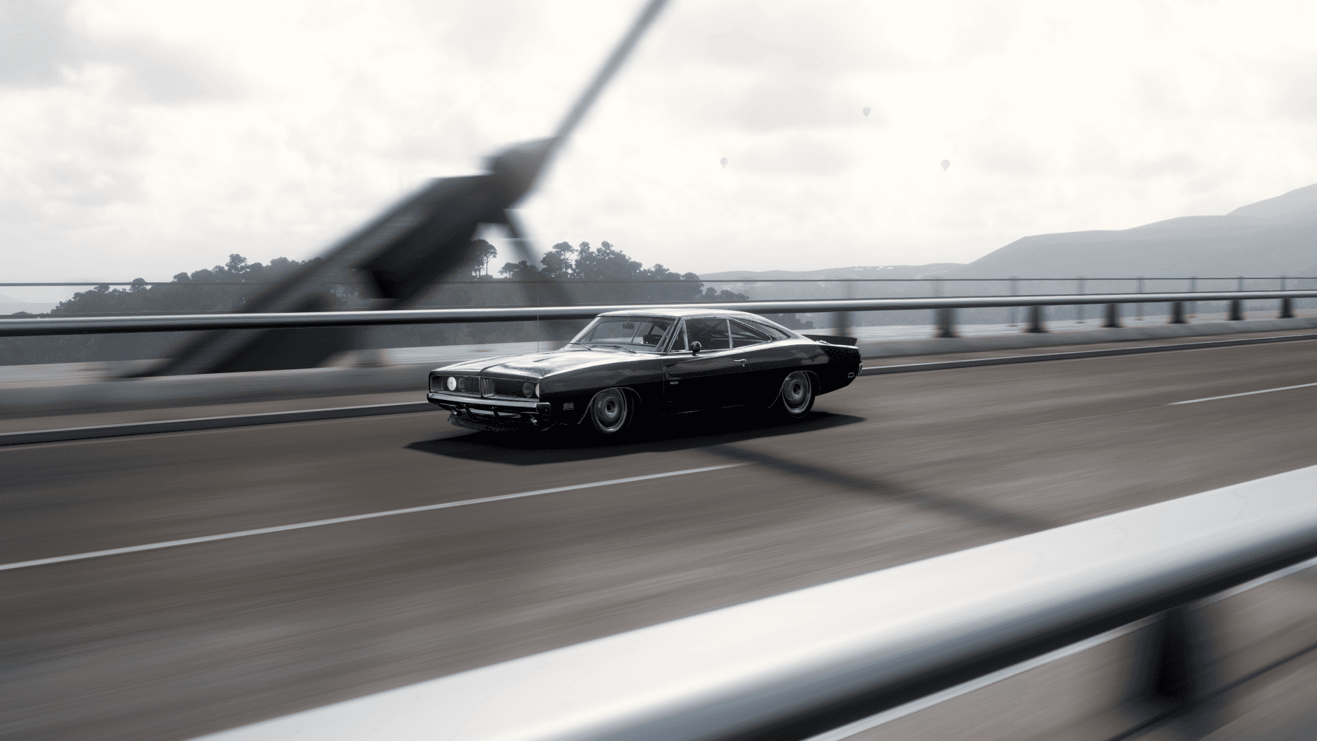 Forza 桌布 壁紙 — 一輛黑色經典肌肉車在陰天天空下以動態模糊強調速度疾馳過橋。