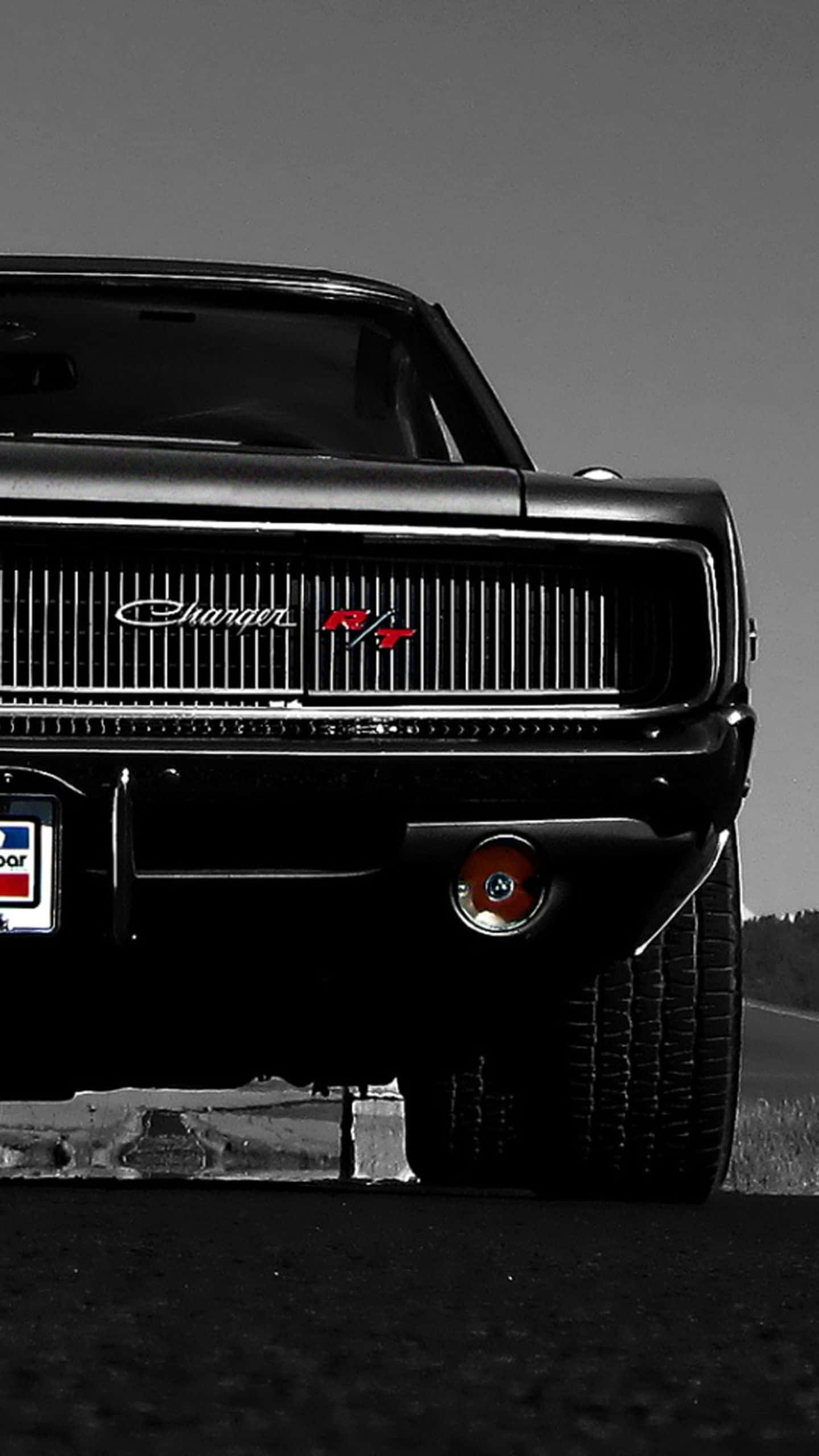 Dodge 桌布 壁紙 — 一輛黑色經典道奇 Charger RT，帶有紅色點綴和復古車牌，停在路邊。