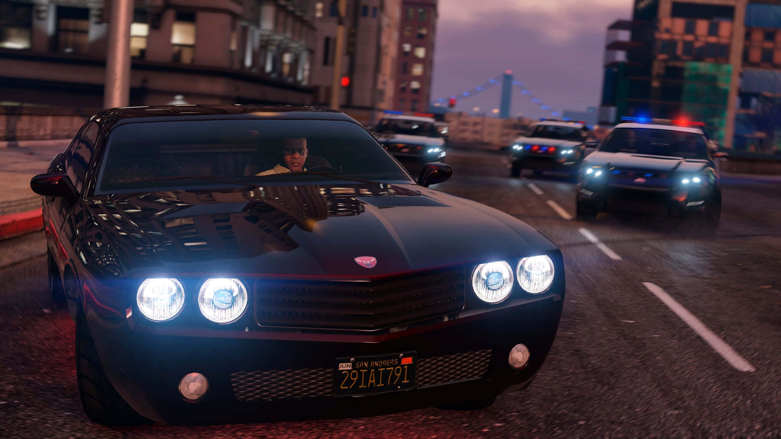 Grand Theft Auto V 桌布 壁紙 — 一輛黑色肌肉車亮著發光的頭燈，在黃昏時分被警車追趕，飛馳穿過城市街道。