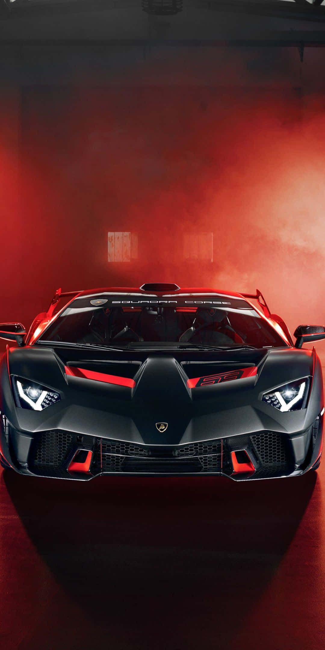 Pixel 3 Lamborghini 桌布 壁紙 — 一輛黑色藍寶堅尼 Squadra Corse 超級跑車帶有紅色點綴，在煙霧瀰漫的車庫中，在戲劇性的紅色燈光下閃耀。