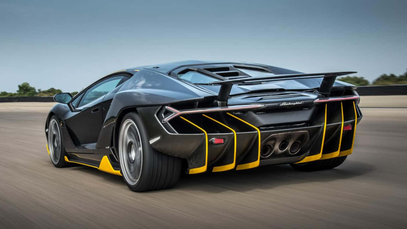 Cool Lamborghinis 桌布 壁紙 — 一輛黑色藍寶堅尼帶有黃色點綴，在晴朗天空下的賽道上疾馳。
