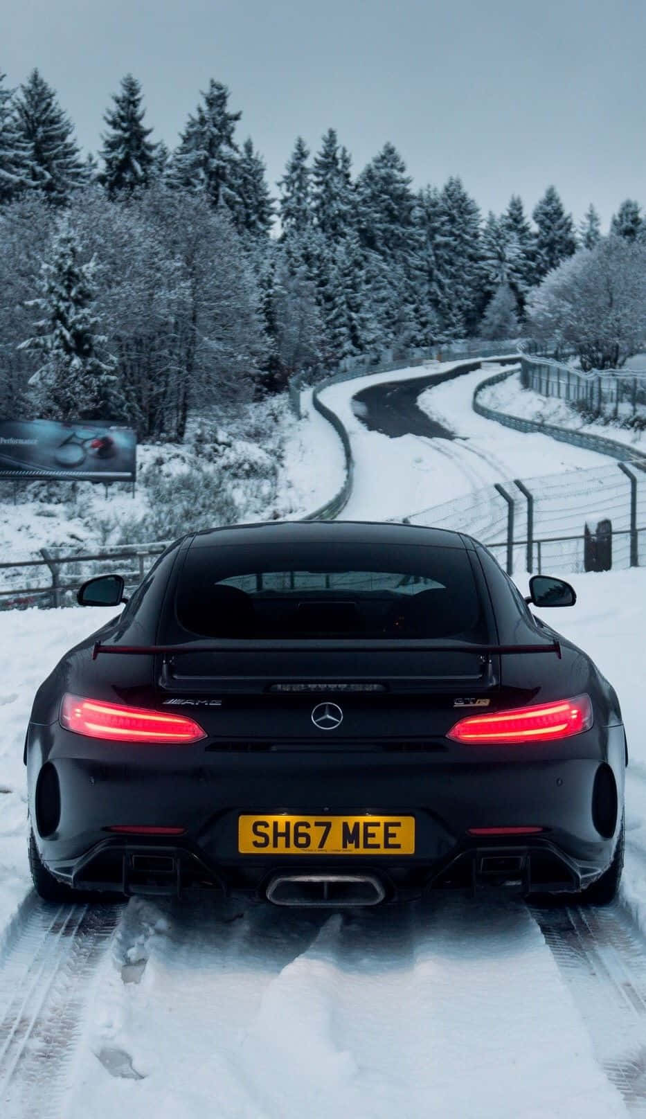 黑色 桌布 壁紙 — 一輛黑色賓士AMG GT R，亮著紅色尾燈，在黃昏時分駛過白雪覆蓋的森林道路。