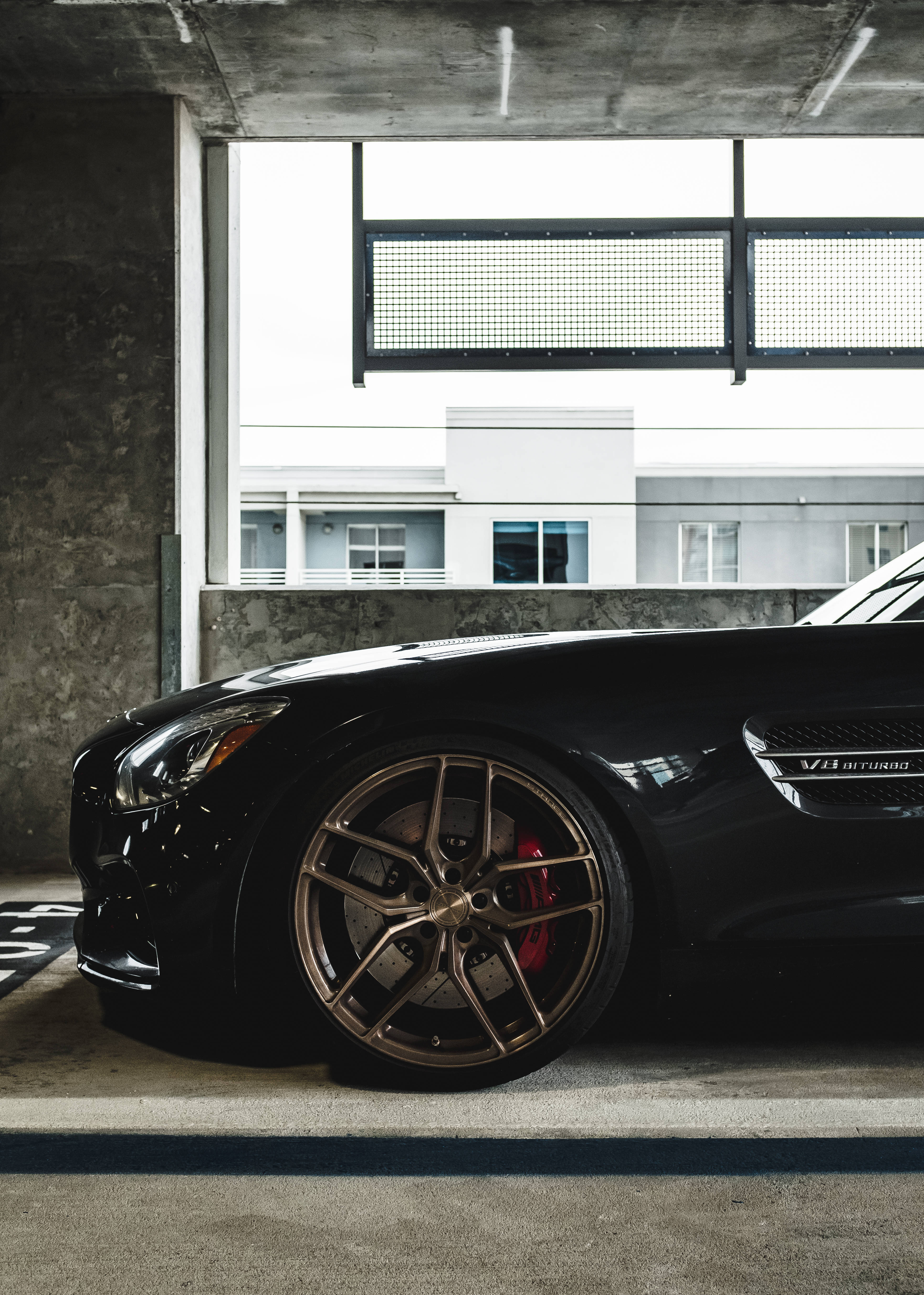 Mercedes Amg 桌布 壁紙 — 一輛黑色賓士AMG GT停在混凝土車庫，配金色輪圈和紅色制動卡鉗。