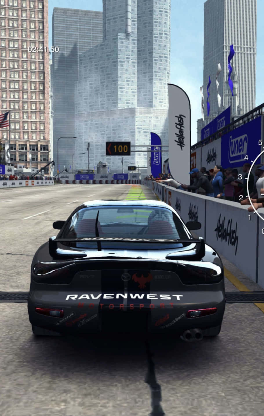 iPhone X Grid Autosport 桌布 壁紙 — 一輛黑色賽車在街頭賽車活動中，沿著兩旁高樓大廈和歡呼人群的城市街道飛馳。