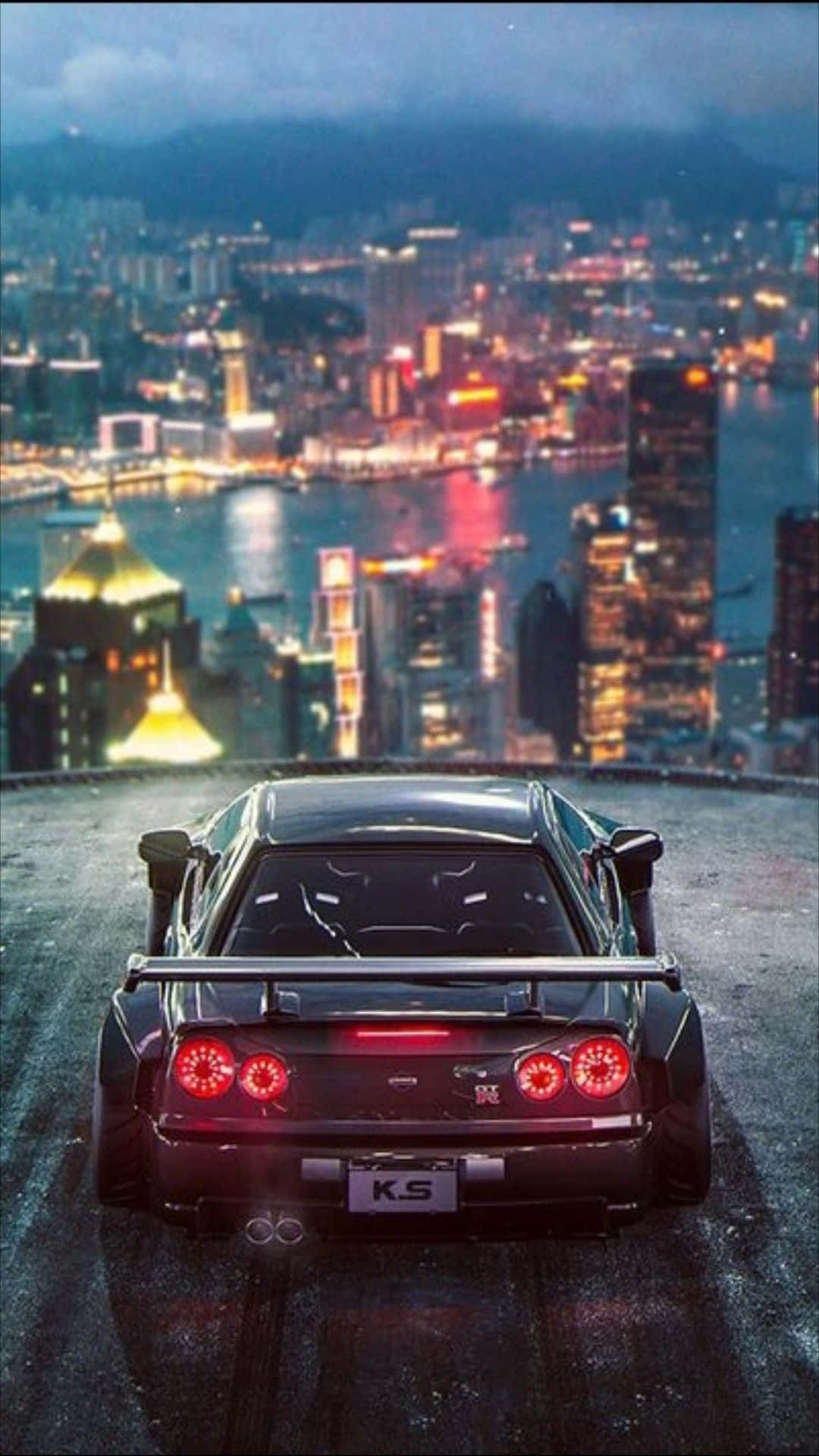 JDM iPhone 桌布 壁紙 — 一輛黑色跑車，帶有發光的紅色尾燈，停在小山頂上，俯瞰著暮色中充滿活力的霓虹燈城市景觀。