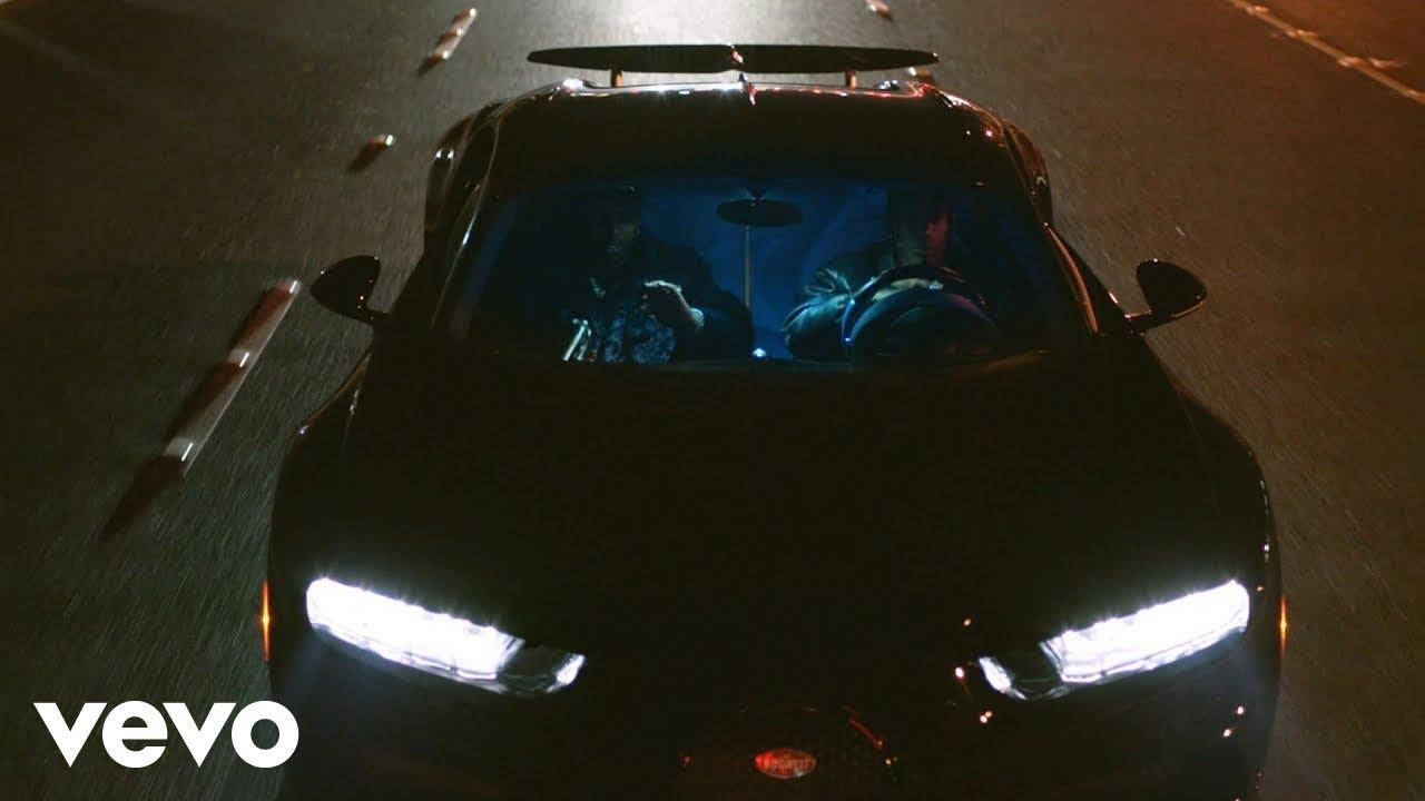 音樂 桌布 壁紙 — 一輛黑色跑車亮著發光頭燈，在夜間沿著黑暗道路疾馳，車內有兩個人。