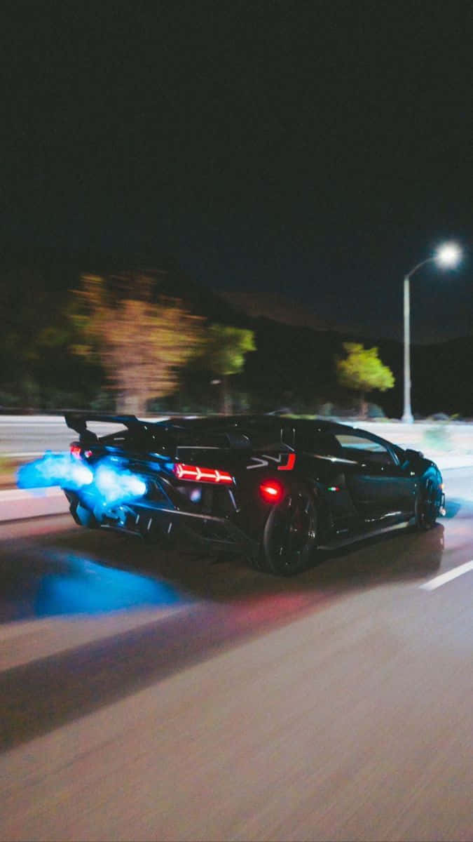 Minimalist Car 桌布 壁紙 — 一輛黑色跑車帶有發光藍色排氣火焰，在路燈下的夜街上疾駛。