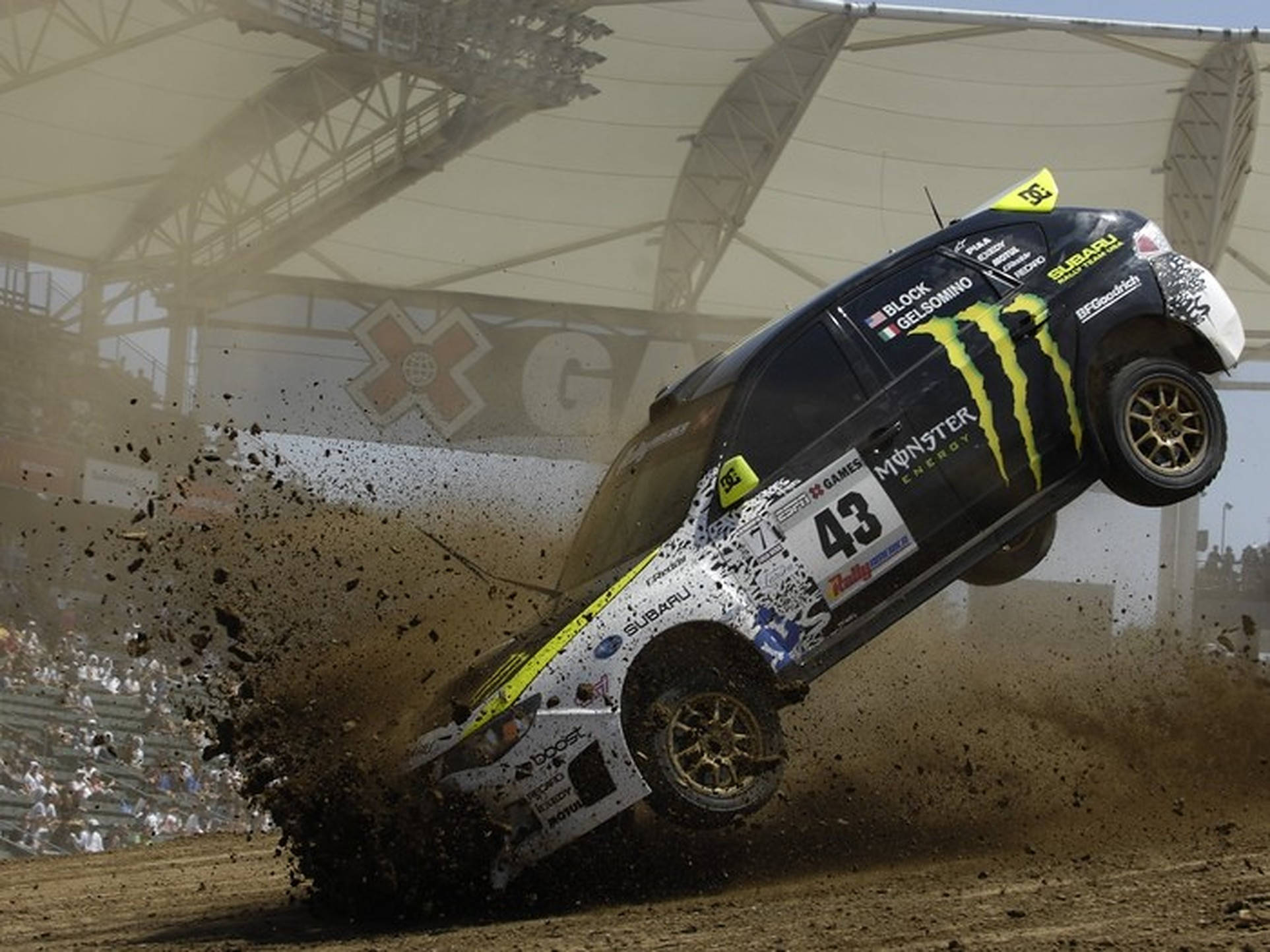 Dirt 3 桌布 壁紙 — 一輛黑黃色的拉力賽車在泥地賽道上飛躍，在體育場燈光下濺起泥漿。