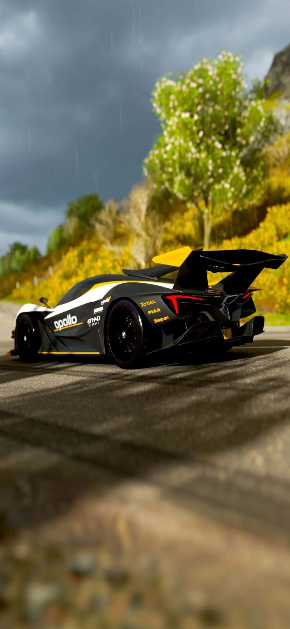 電玩遊戲 桌布 壁紙 — 一輛黑黃色的阿波羅 Intensa Emozione 超級跑車在暴風雨的天空下，沿著濕滑的山路疾馳，周圍是鮮豔的秋葉。