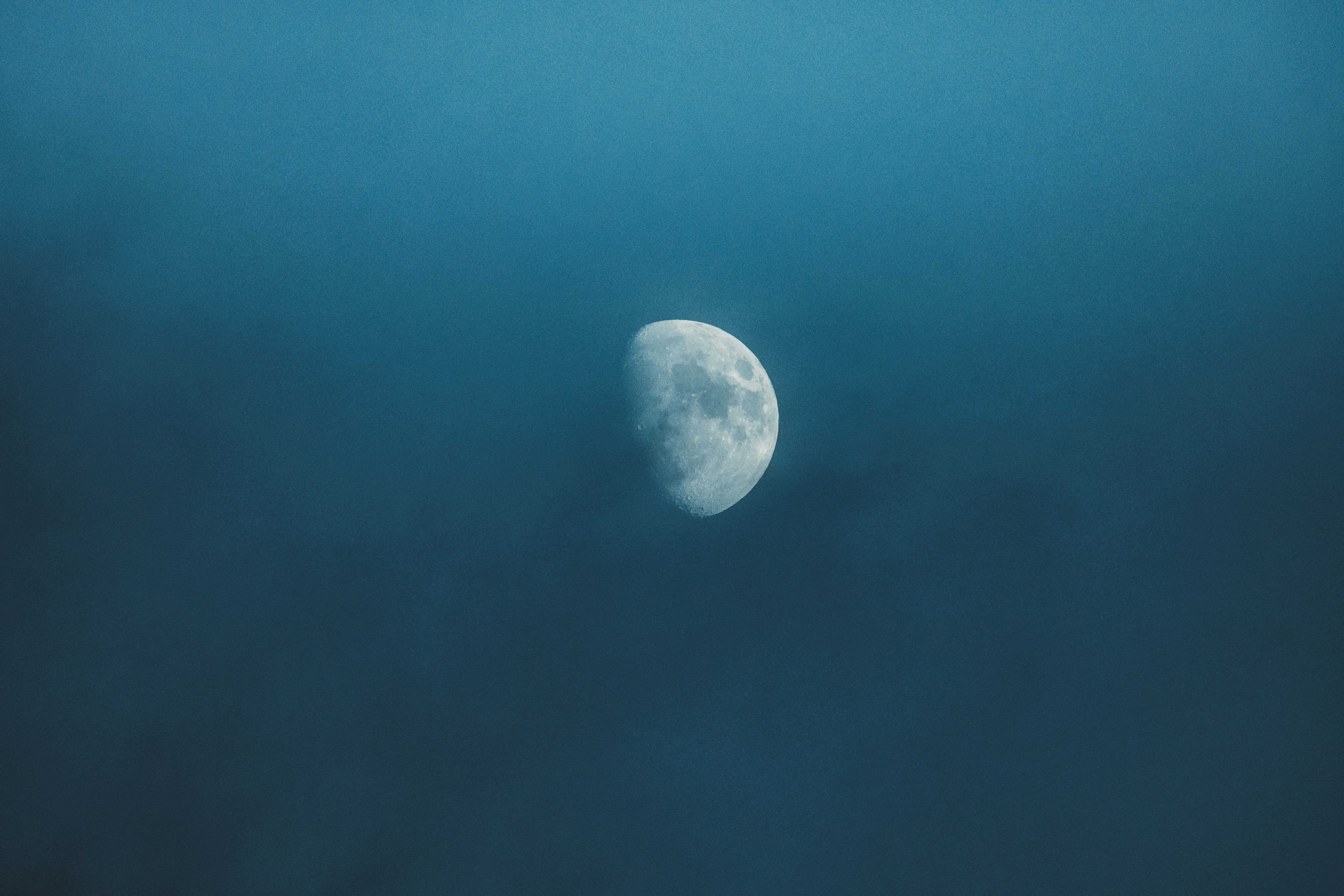 月光 桌布 壁紙 — 一輪寧靜的半月在佈滿縷縷雲彩的深藍色暮色天空中柔和地發光。
