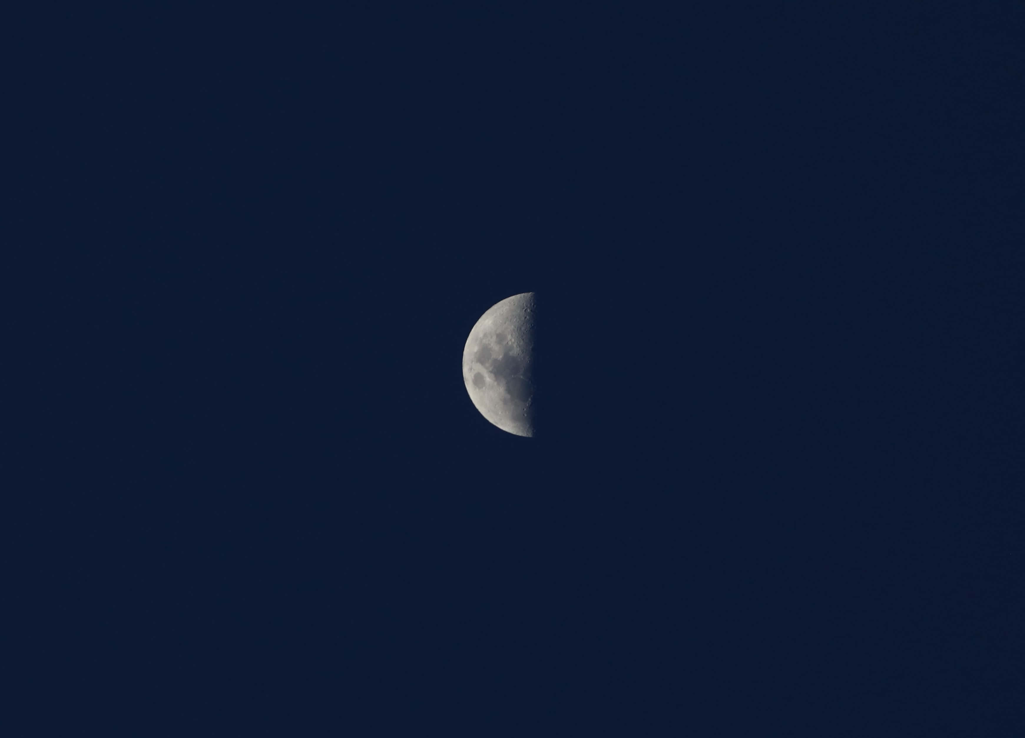月光 桌布 壁紙 — 一輪寧靜的半月在沒有星星的深藍色夜空下柔和地發光。