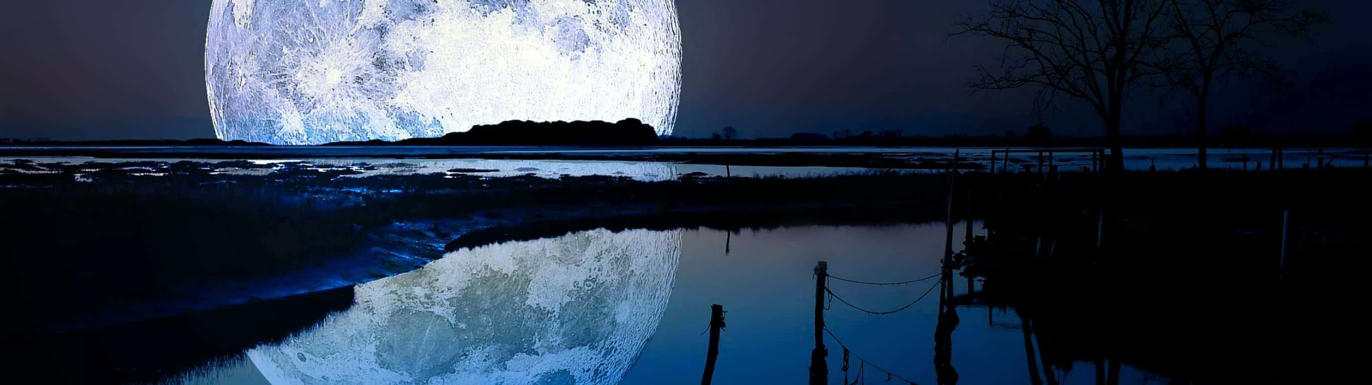 在漆黑的夜空下，一輪巨大的月亮倒映在平靜的水面上。 — 超寬 GIF 壁紙