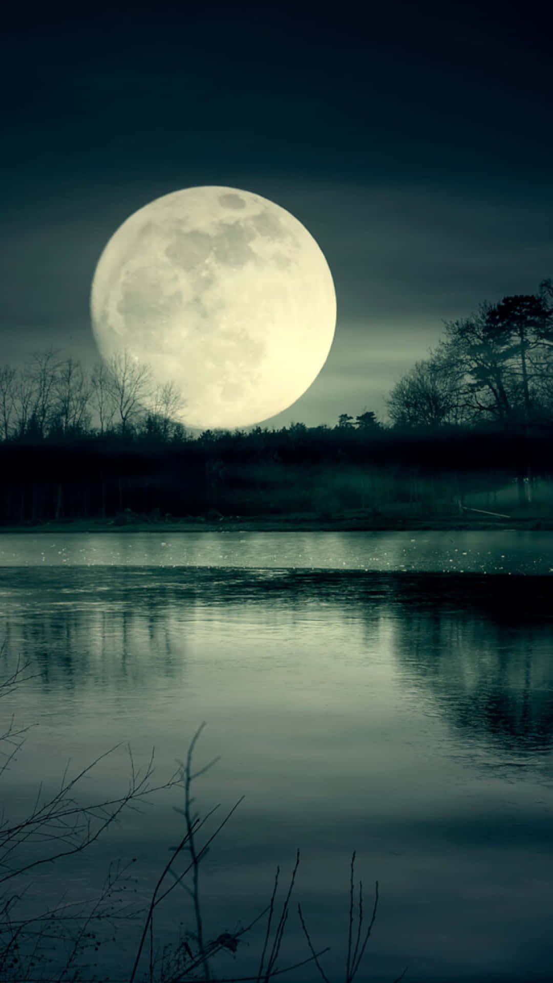 月夜星空 桌布 壁紙 — 一輪巨大明亮的滿月懸掛在寧靜的湖面上，在黑暗陰沉的天際下反射出它的光芒。