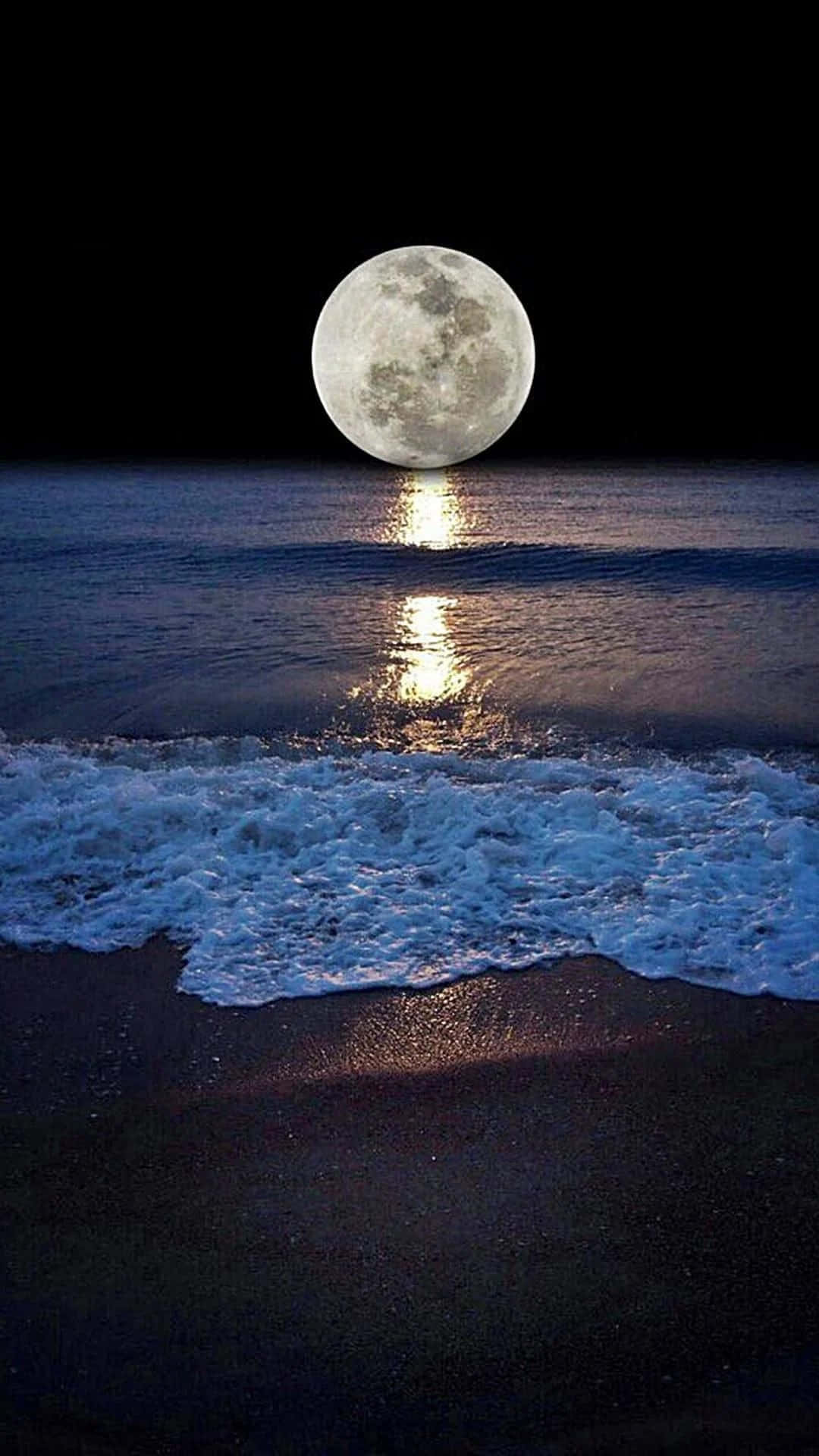 Beautiful Moon 桌布 壁紙 — 一輪巨大的滿月從黑暗的海洋上升起，在輕柔拍打黑色沙灘的波浪上投射出一條閃爍的光路。