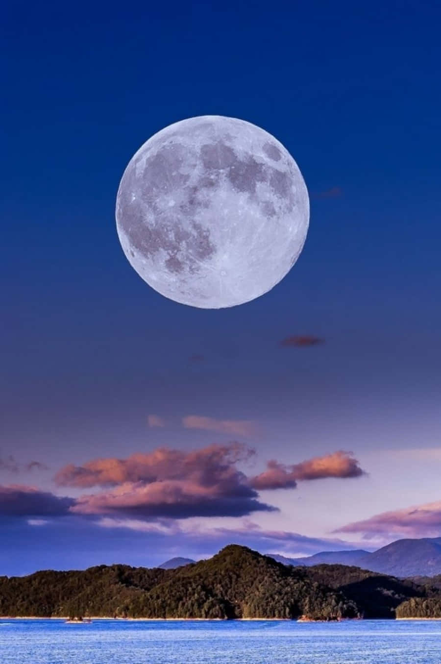 Beautiful Moon 桌布 壁紙 — 一輪巨大的滿月懸掛在平靜的海洋和森林覆蓋的島嶼之上，天空在暮色中被粉紅色和紫色的雲彩渲染。