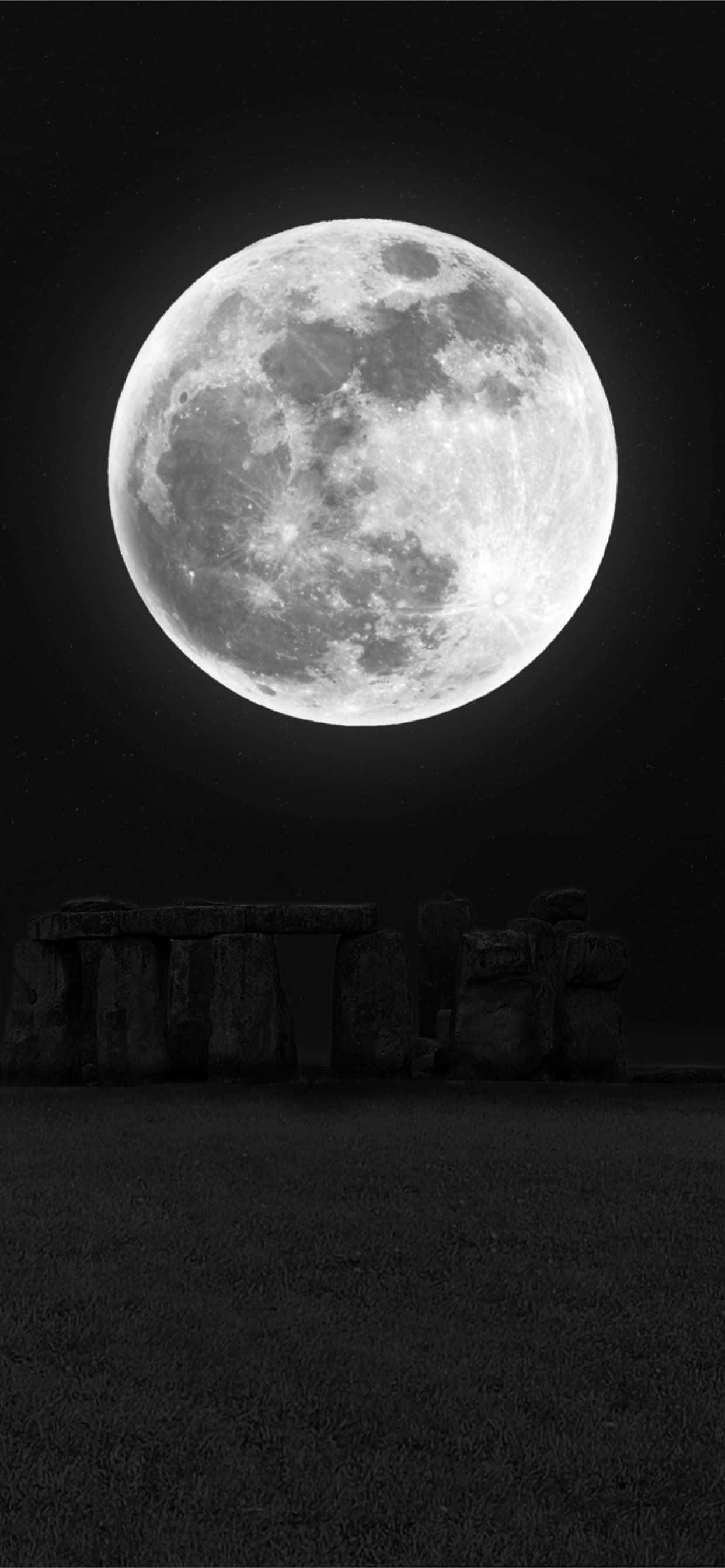 Moon And Stars Phone 桌布 壁紙 — 一輪巨大的滿月籠罩在古老的巨石陣石圈之上，背景是繁星點點的夜空。