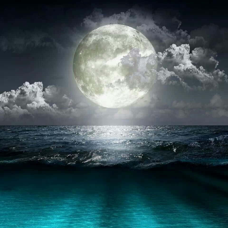 Beautiful Moon 桌布 壁紙 — 一輪巨大的發光月亮在波濤洶湧的海洋上升起，戲劇性的雲層在水面上投下陰影。