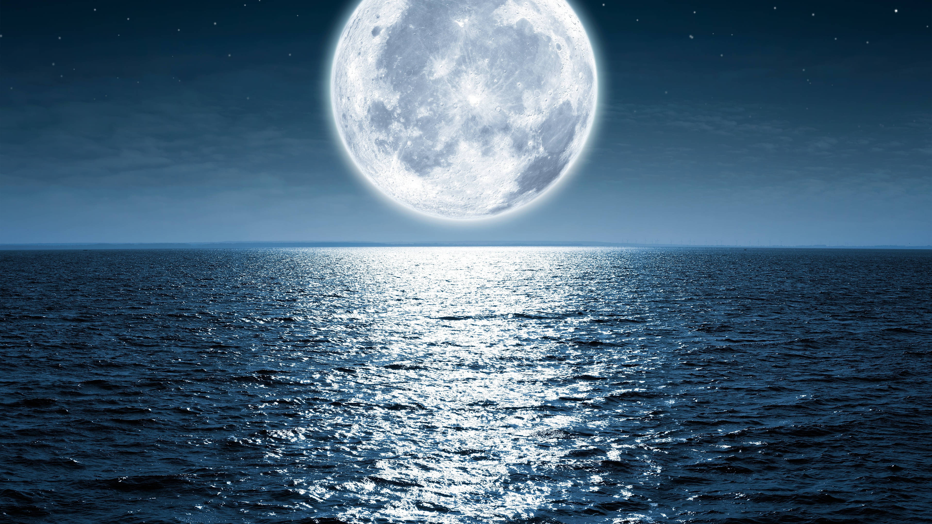 moonlight 4K 桌布 壁紙 — 一輪巨大的發光月亮懸掛在黑暗的海洋上空，在繁星點點的夜空下反射出銀色的光芒。