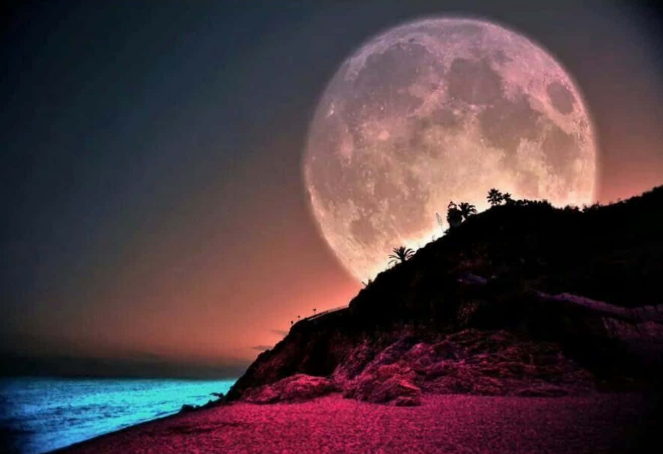 Beautiful Moon 桌布 壁紙 — 一輪巨大的粉紅色月亮在暮色中升起，旁邊是發光的藍綠色海洋和剪影懸崖。