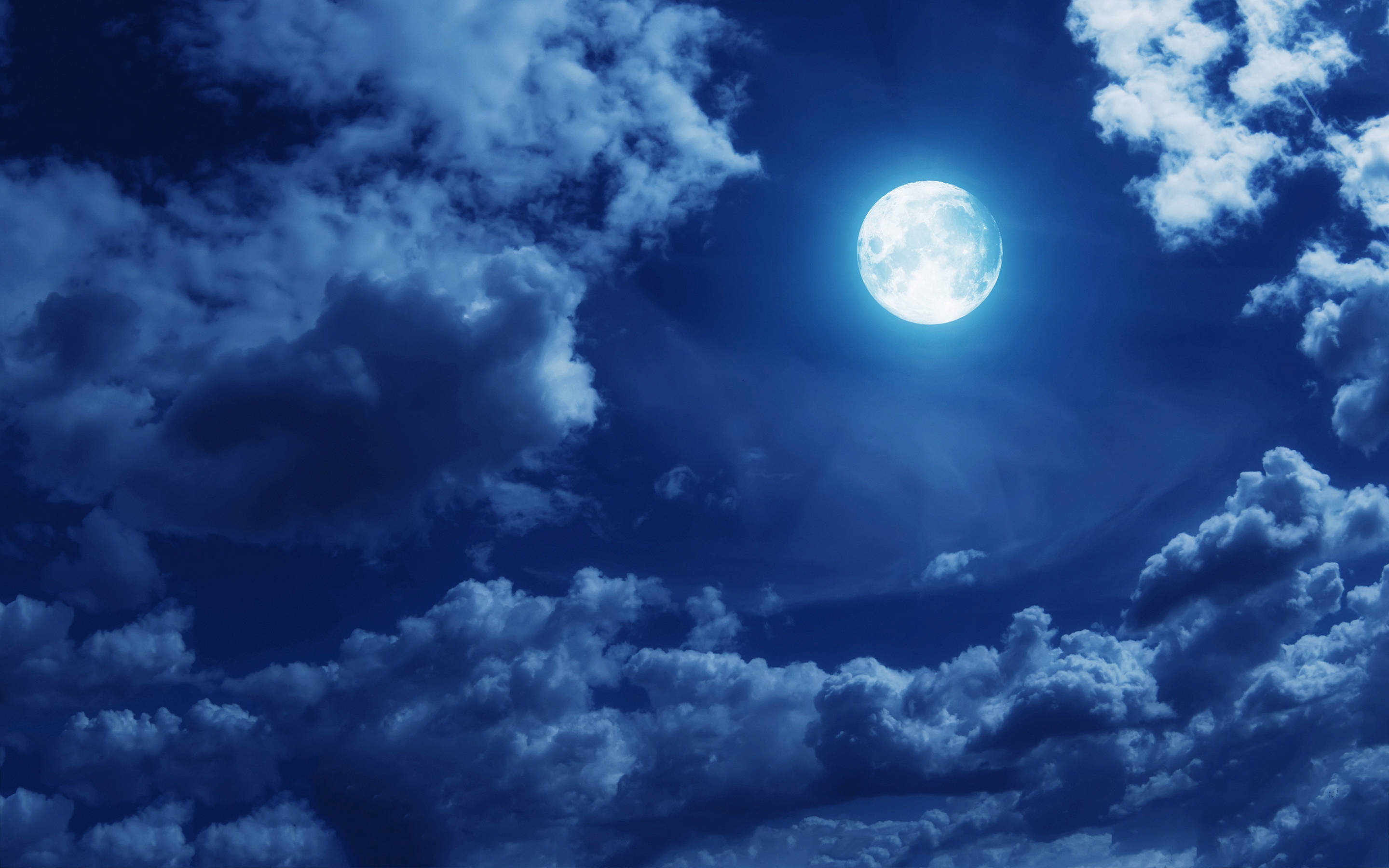 美學雲朵 桌布 壁紙 — 一輪明亮的滿月在夜間透過充滿紋理藍色雲層的戲劇性天空閃耀。