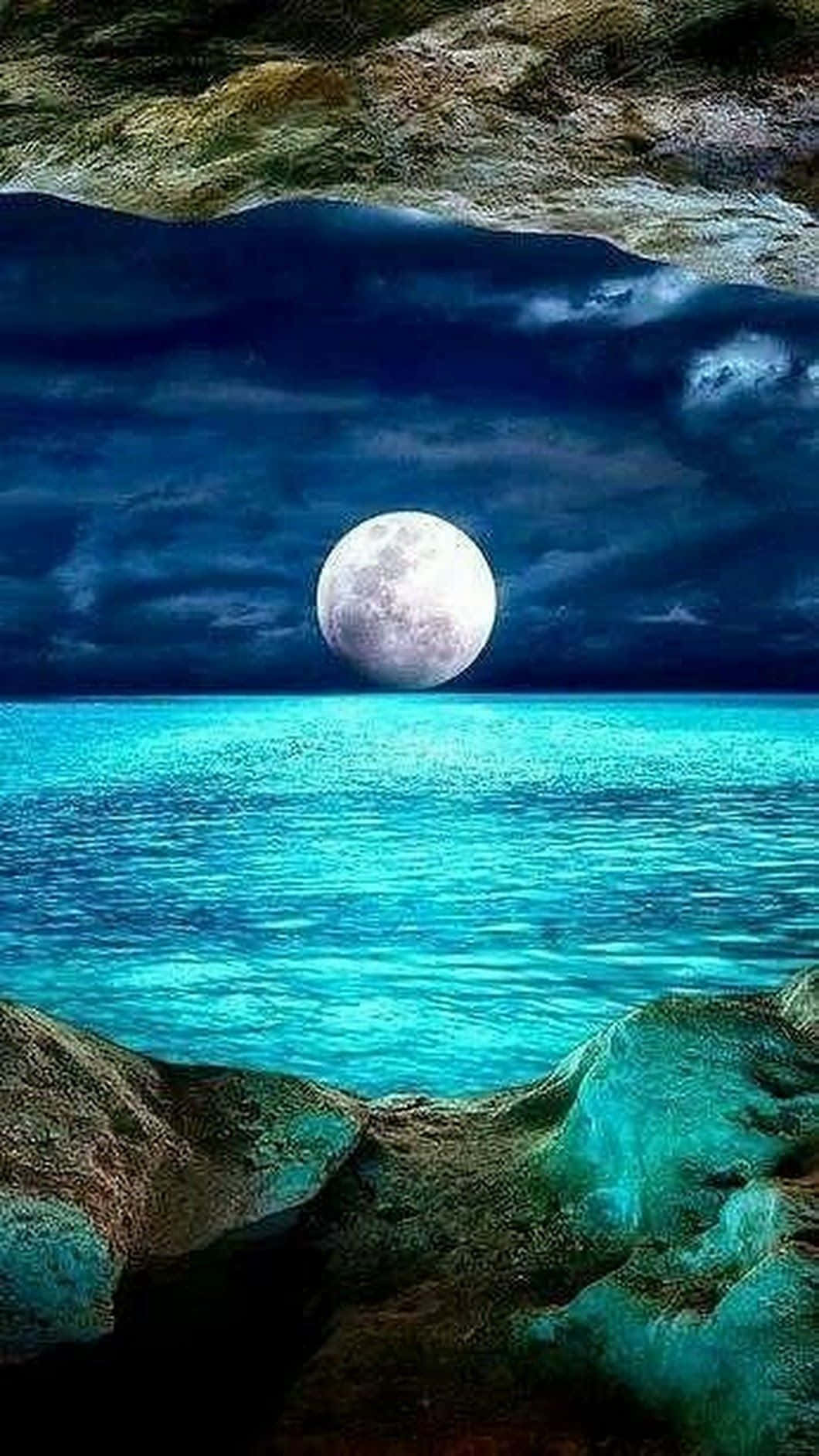 Beautiful Moon 桌布 壁紙 — 一輪明亮的滿月在暴風雨夜空中升起，映襯著崎嶇岩石環繞的充滿活力的碧綠海洋。