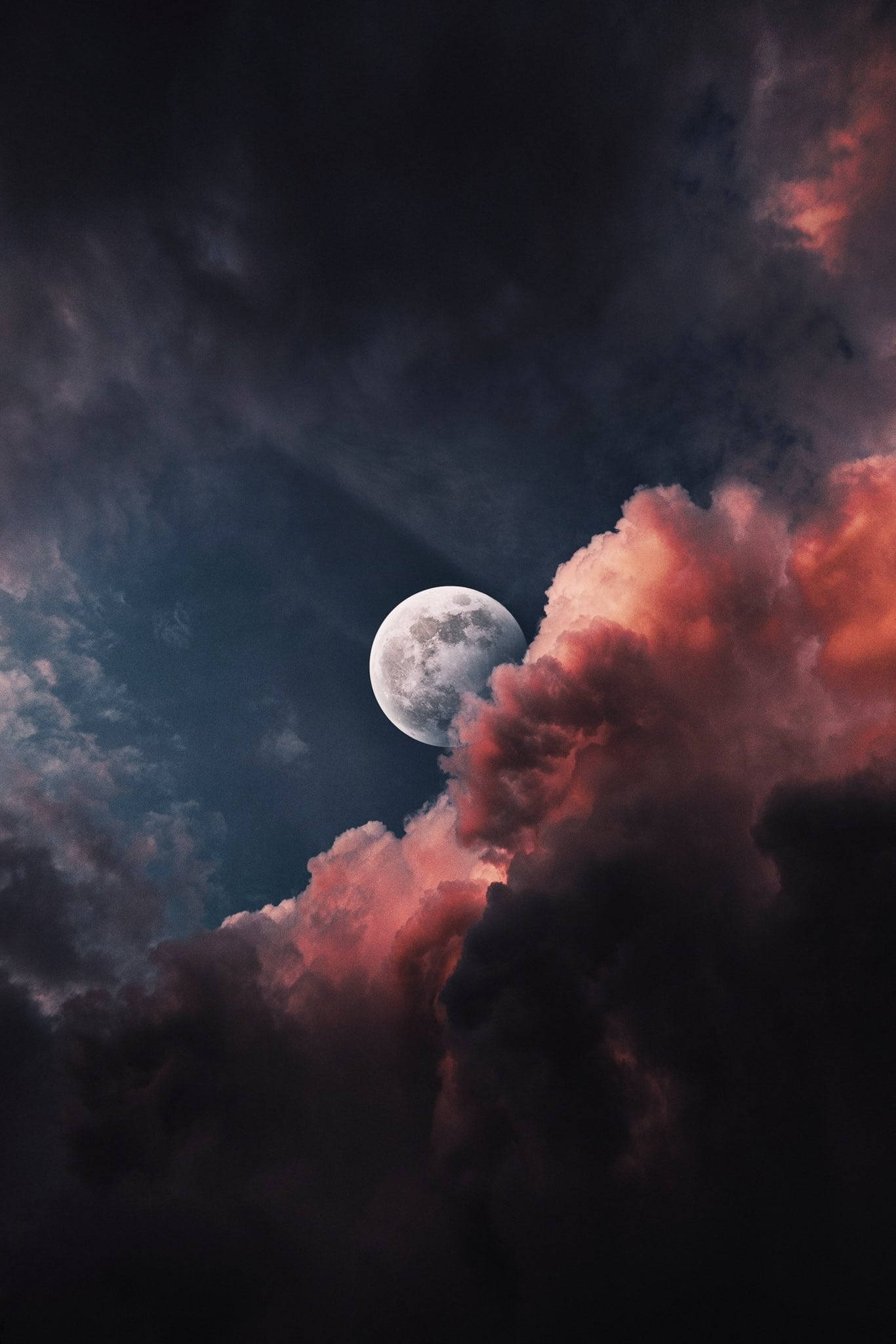 夜空 桌布 壁紙 — 一輪明亮的滿月在染上熾熱粉紅和深靛藍暮色的戲劇性雲層後發光。